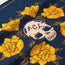 A blue fabric from the Yellow Rose Collection features bright yellow roses and a white skull with ACL written on its forehead, surrounded by leaves and orange dotted accents along the edge—perfect for Howler Bandanas at the ACL Festival.