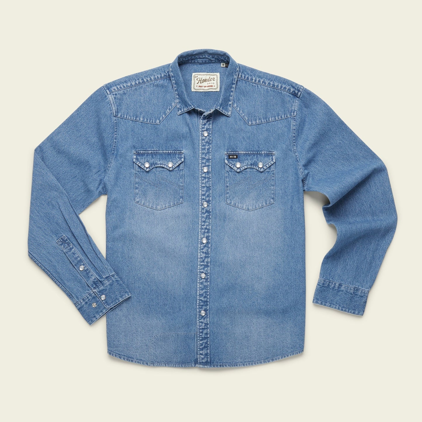 A light blue denim button-up shirt with long sleeves, two front chest pockets with button flaps, and white buttons showcases versatile style, laid flat on a plain light background. - View 9
