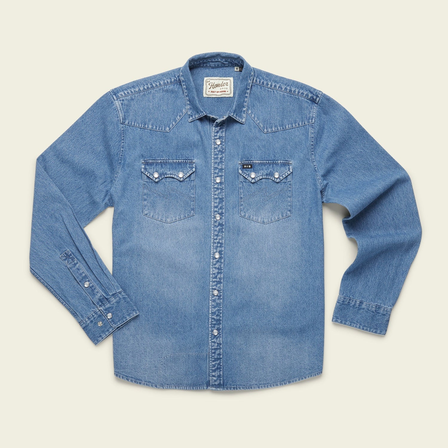 A light blue denim button-up shirt with long sleeves, two front chest pockets with button flaps, and white buttons showcases versatile style, laid flat on a plain light background. - View 9