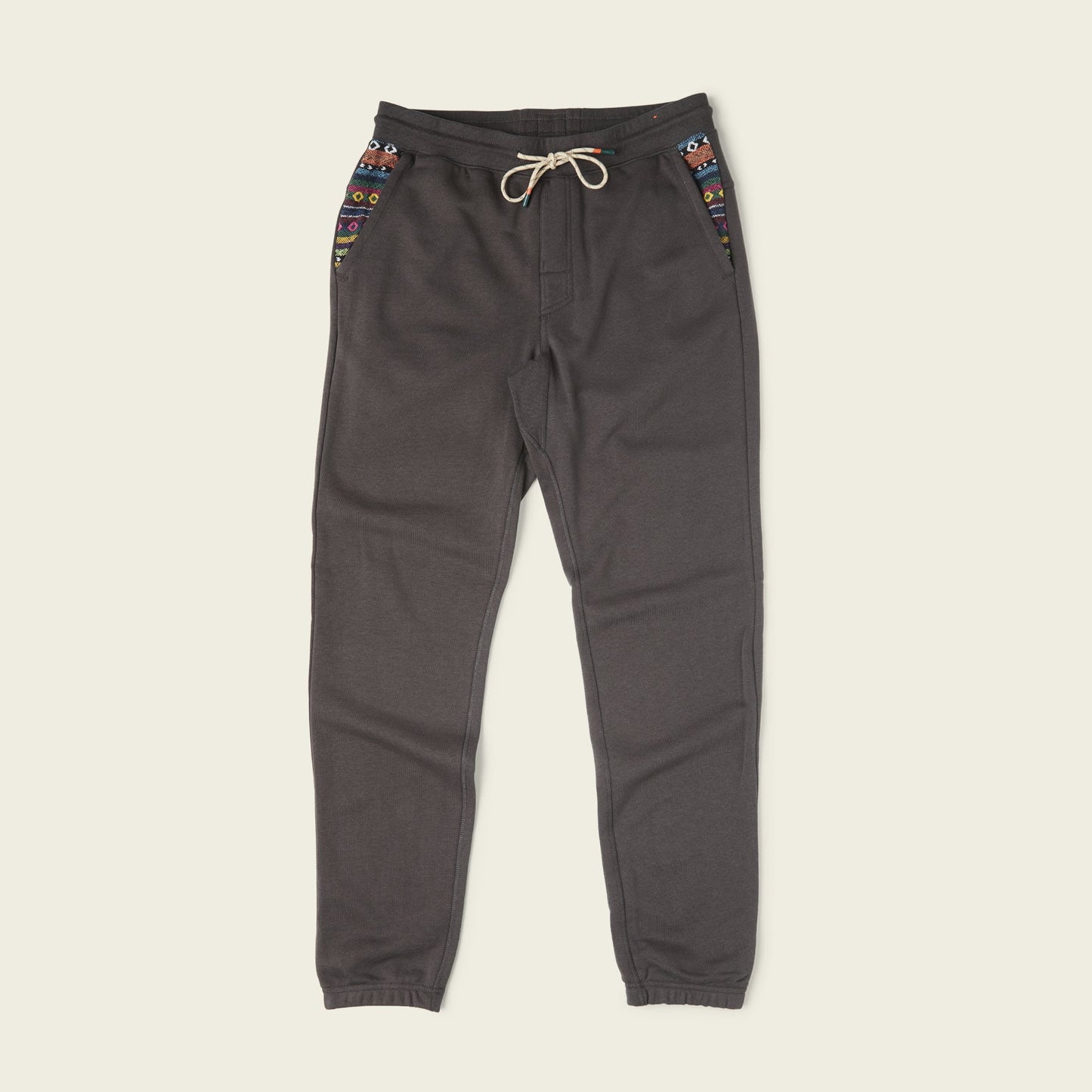 Dark gray Mellow Mono Sweatpants with a drawstring waistband, colorful patterned accents on the pockets, and elastic cuffs, displayed on a plain light background. - View 1