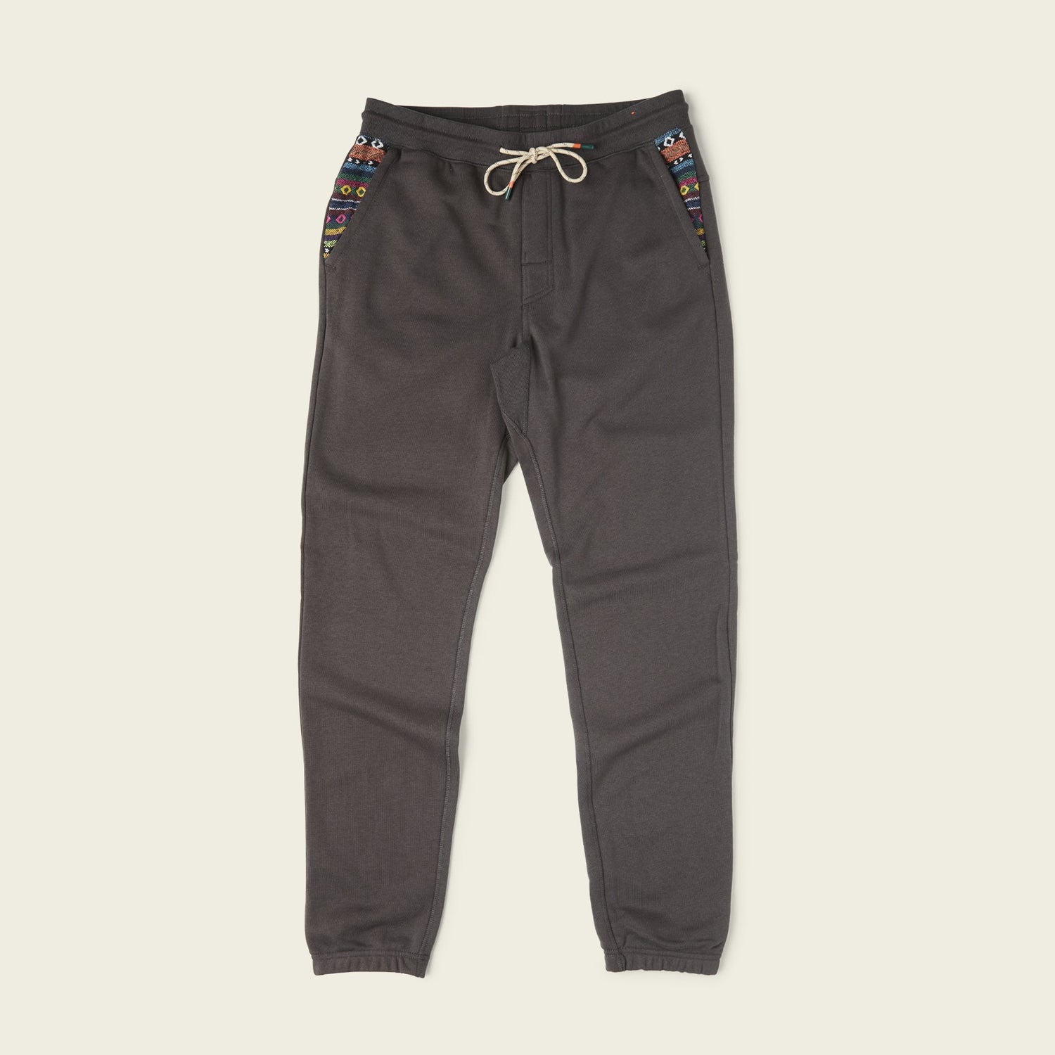 Dark gray Mellow Mono Sweatpants with a drawstring waistband, colorful patterned accents on the pockets, and elastic cuffs, displayed on a plain light background. - View 1