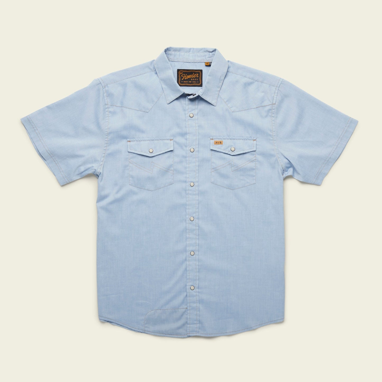 Light blue short-sleeve H Bar B snapshirt with pearl snaps, two front chest pockets, a pointed collar, and a small brown label above the left pocket, laid flat on a cream background. - View 7