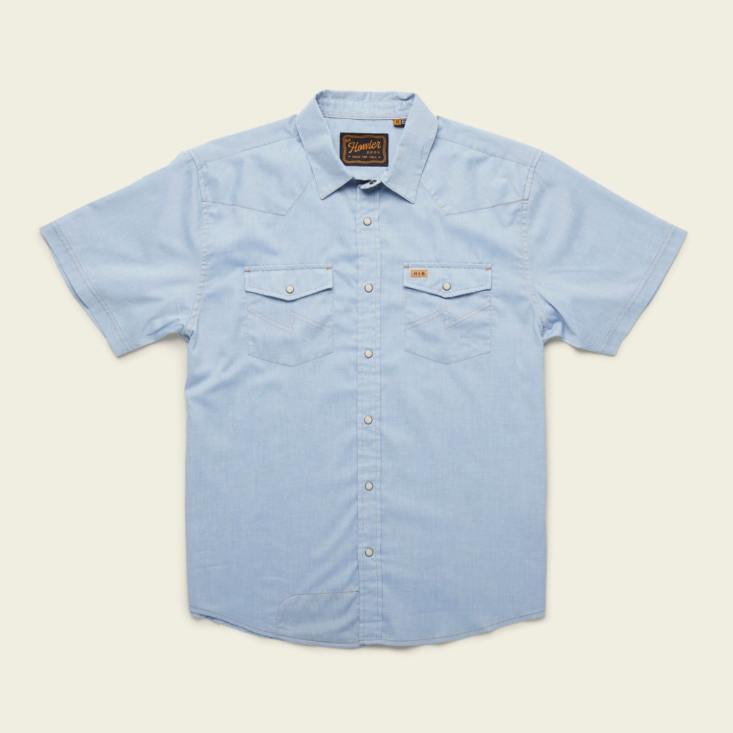 Light blue short-sleeve H Bar B snapshirt with pearl snaps, two front chest pockets, a pointed collar, and a small brown label above the left pocket, laid flat on a cream background. - View 8