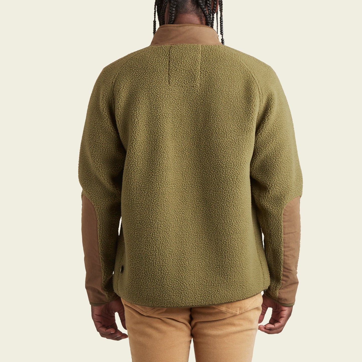 A person wearing a green Howler Crozet fleece jacket with brown elbow patches and tan pants is shown from the back against a plain light background. - View 5