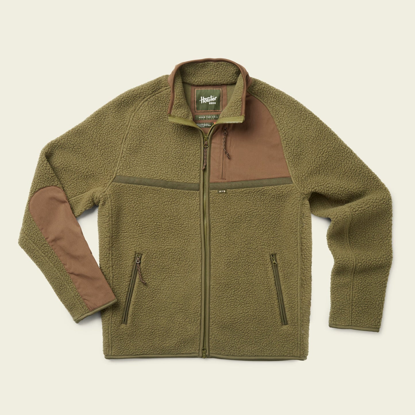 Olive green polyester fleece jacket with a full front zipper, two zippered side pockets, brown fabric patches on the right shoulder and left elbow, and a green collar with a branded label inside—essential fall outerwear. - View 1