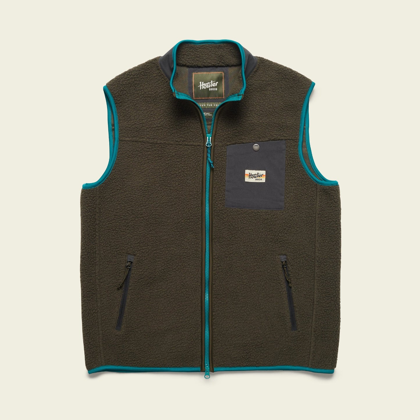 A dark green Chisos Fleece Vest with teal trim, made from high pile fleece. This lightweight vest features a front zipper, two zippered hand pockets, and a black chest pocket with a button and rectangular Howler Bros logo patch. - View 4