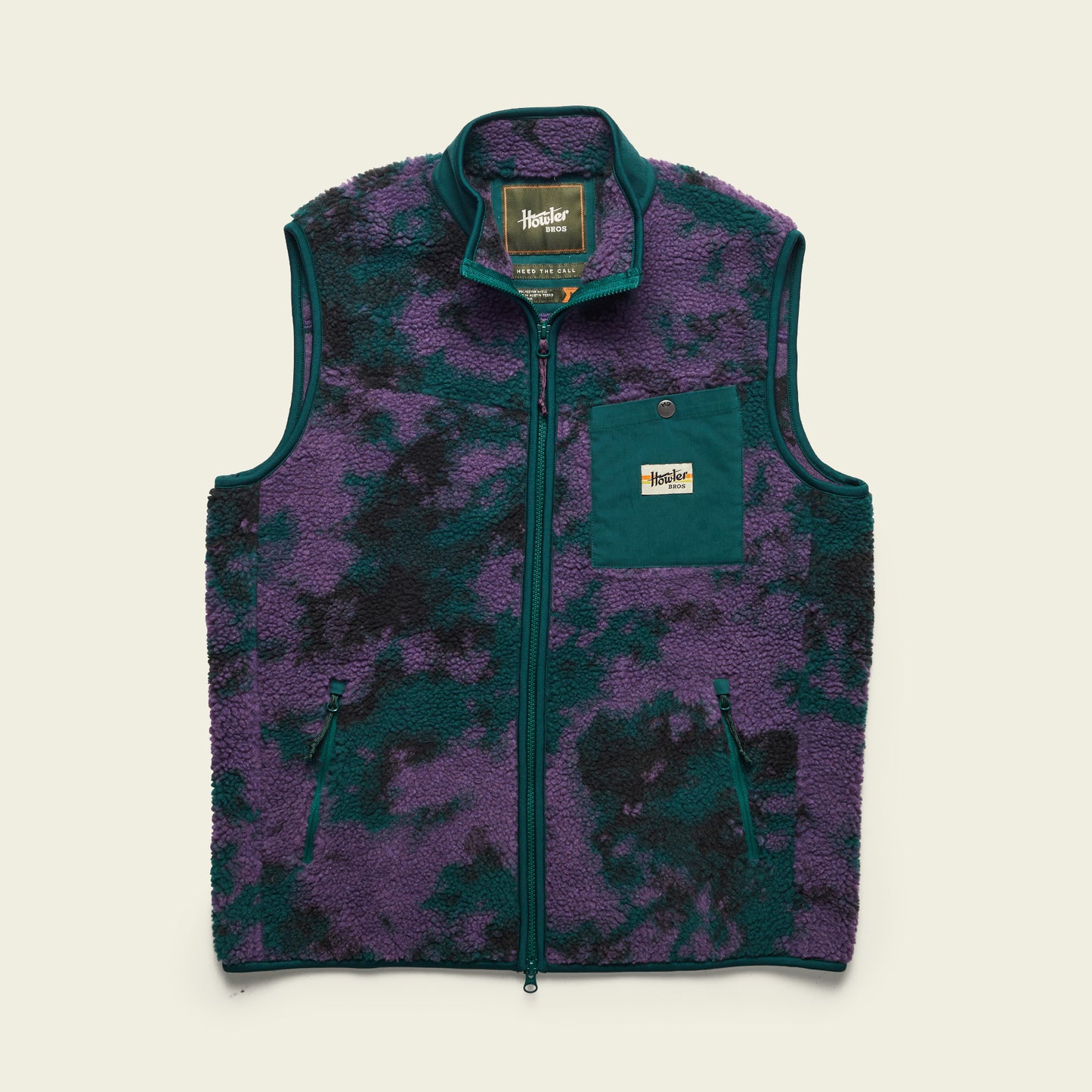 The Chisos Fleece Vest is a lightweight vest featuring high pile fleece, a purple and dark green camouflage pattern, front zipper, two side pockets, and a teal chest pocket with Huckberry label, displayed on a light background. - View 8