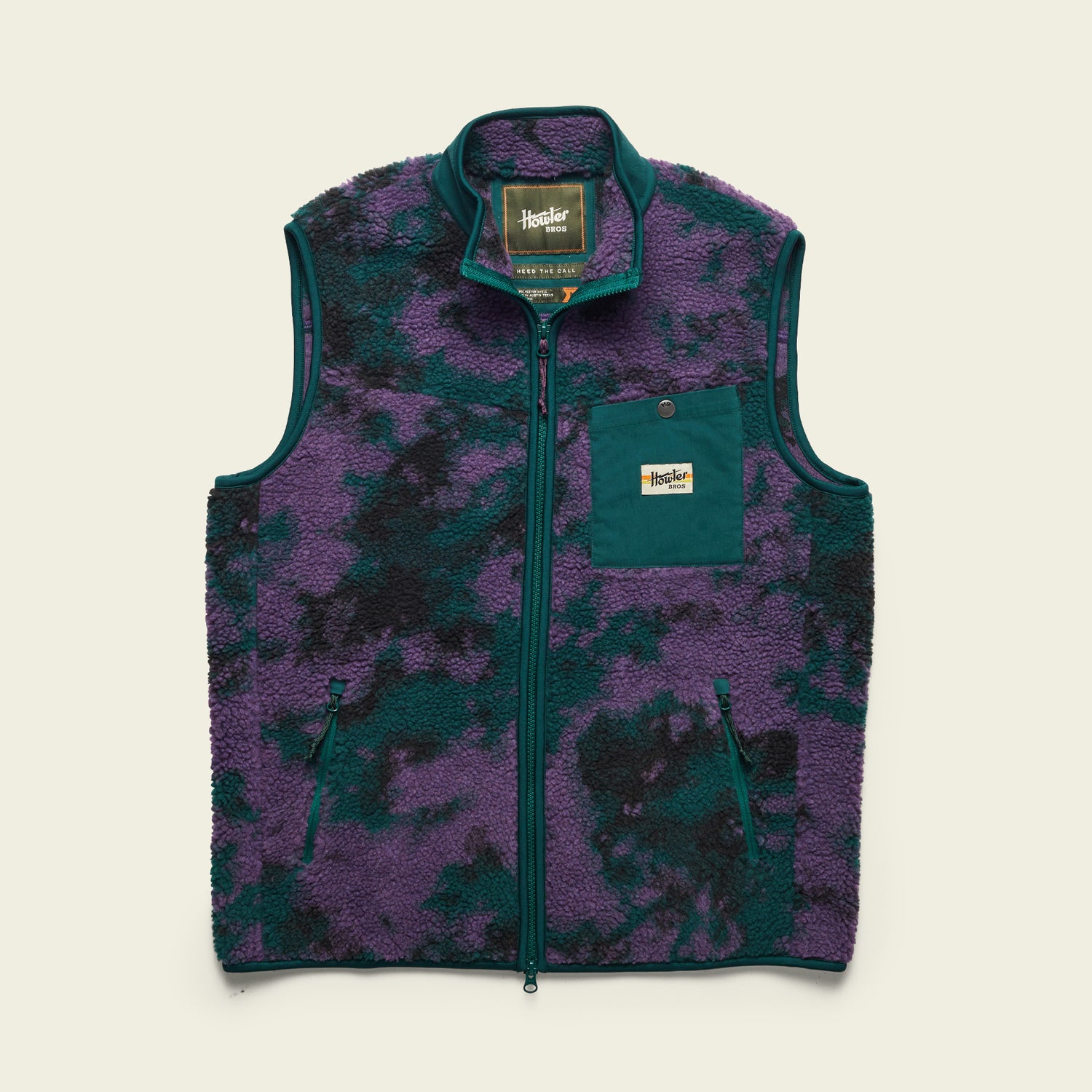 The Chisos Fleece Vest is a lightweight vest featuring high pile fleece, a purple and dark green camouflage pattern, front zipper, two side pockets, and a teal chest pocket with Huckberry label, displayed on a light background. - View 8