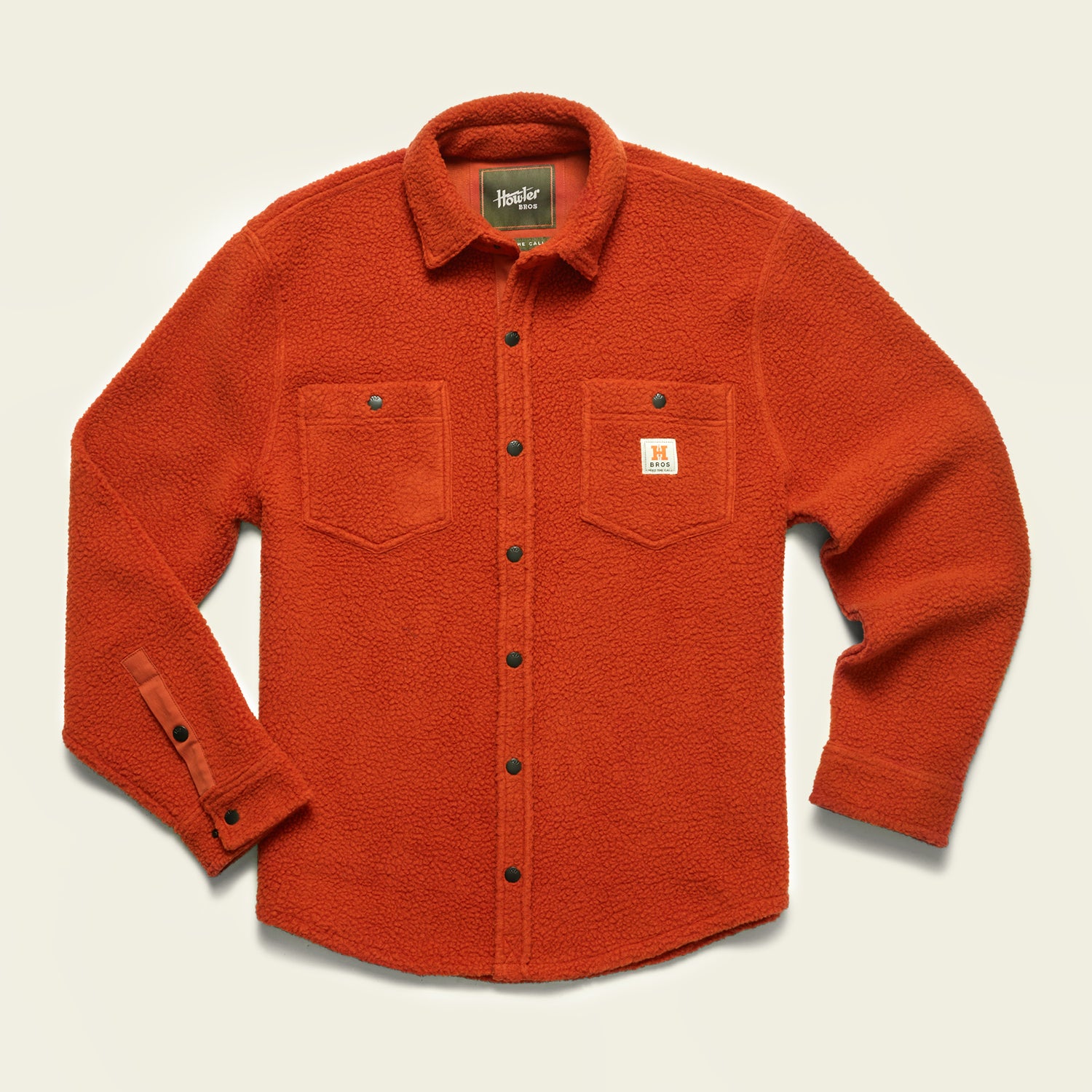 An orange fleece overshirt with two chest pockets, metal snap buttons, and a small white patch on the left pocket displaying an H logo. The shirt has a casual, textured appearance perfect for layering as a casual jacket. - View 3