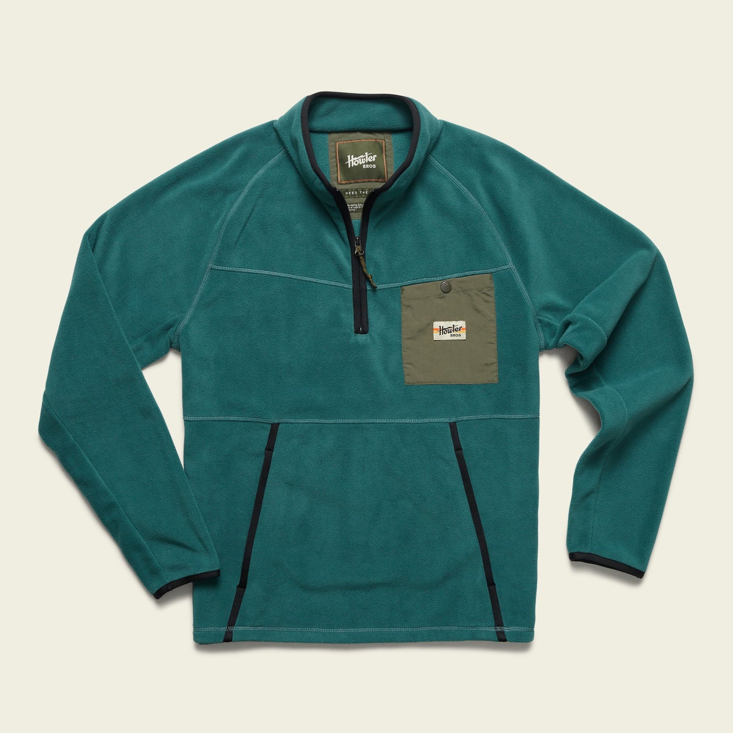 A teal fleece pullover designed for cold weather, featuring a quarter zip, long sleeves, black trim, and an olive green chest pocket with a button flap and a Howler Brothers logo patch. - View 4