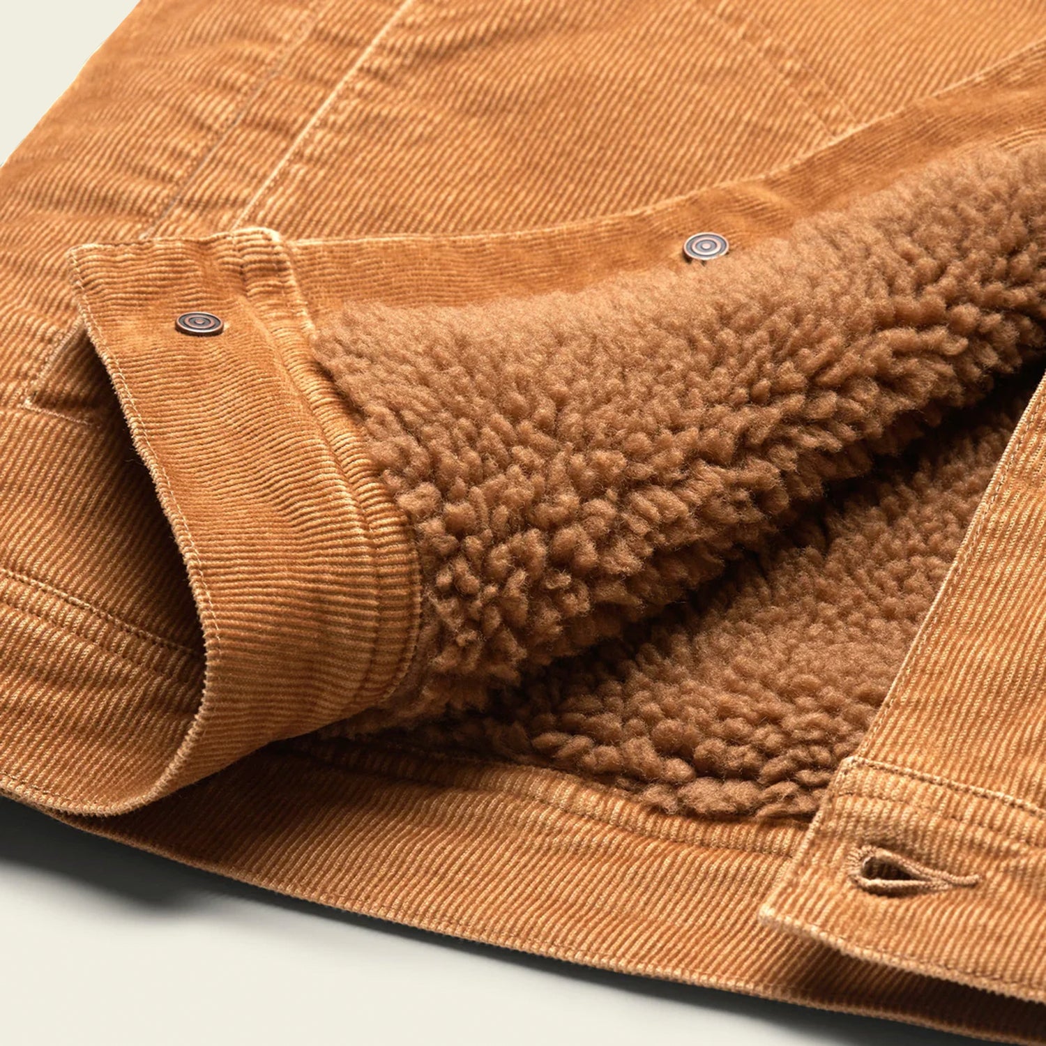 A close-up of the Fuzzy Depot Jacket, a tan corduroy jacket with soft, brown sherpa lining, featuring metal snap buttons and detailed stitching on the fabric. - View 3