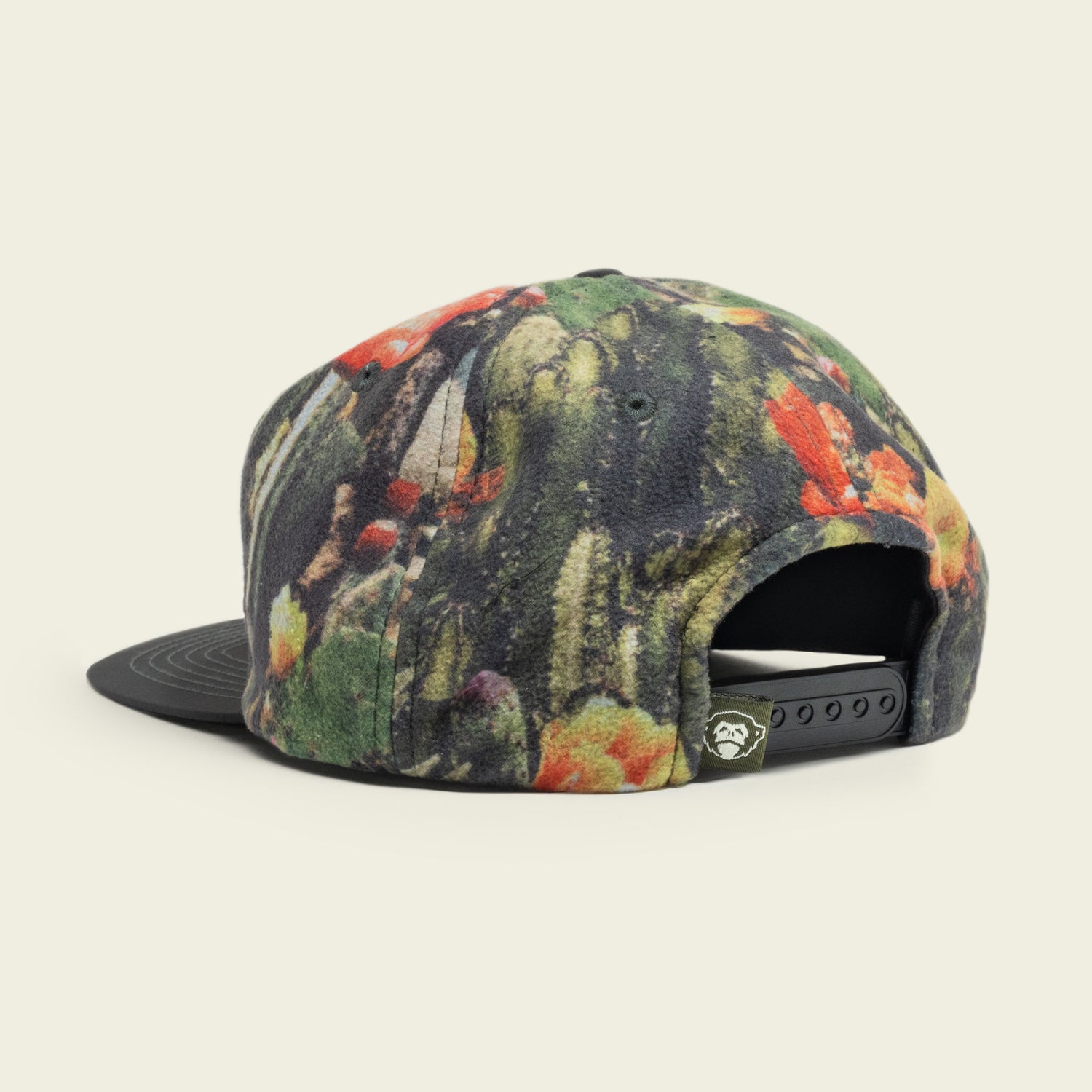 A baseball cap with a colorful, abstract floral pattern features an adjustable snapback closure, small tag with a white logo on the back, and a pliable brim. The unstructured snapback rests on a light, neutral background. - View 2
