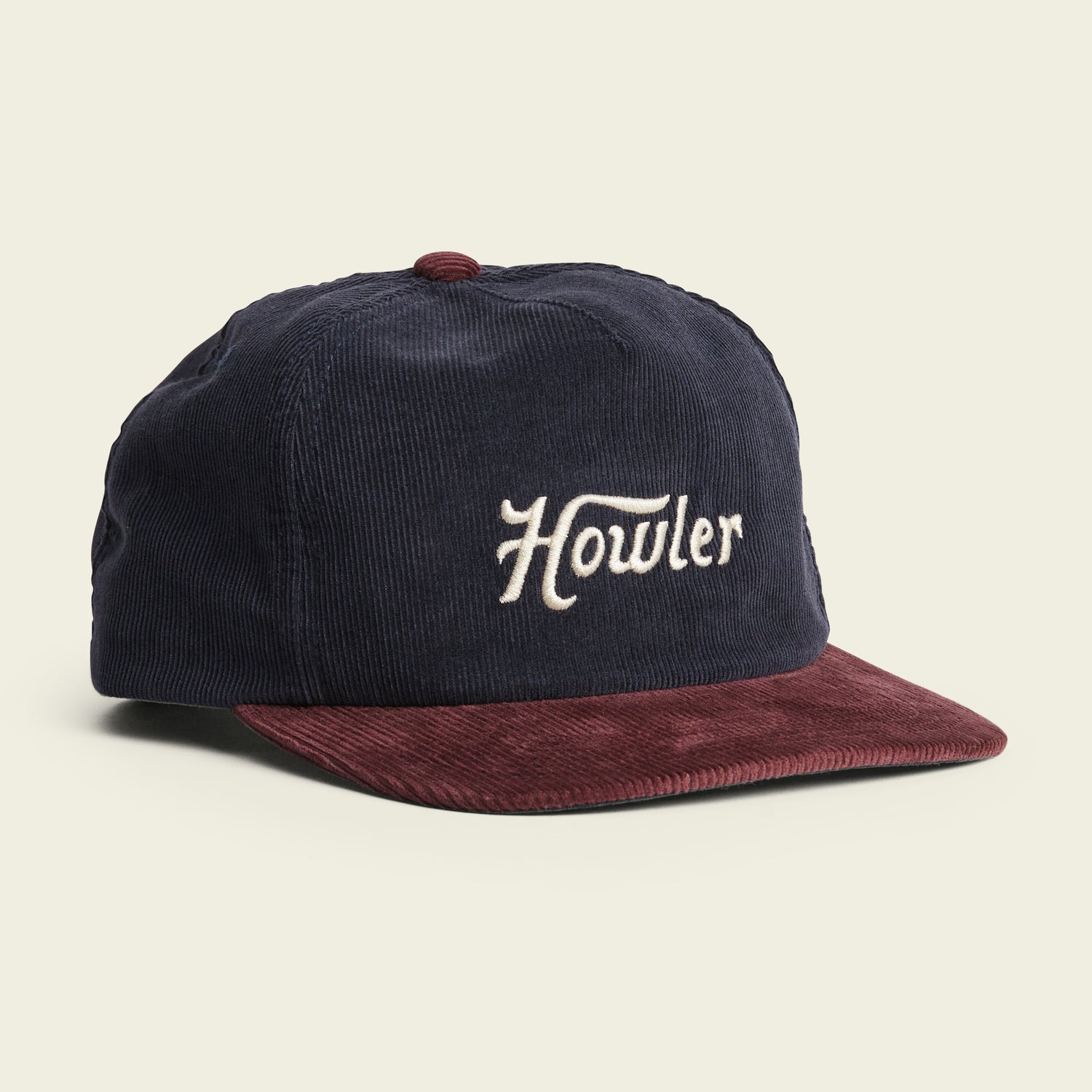 A navy blue corduroy cap with a maroon brim and button, featuring the word Howler embroidered in white script on the front. This soft crown style offers an adjustable snapback closure for a perfect fit. - View 1