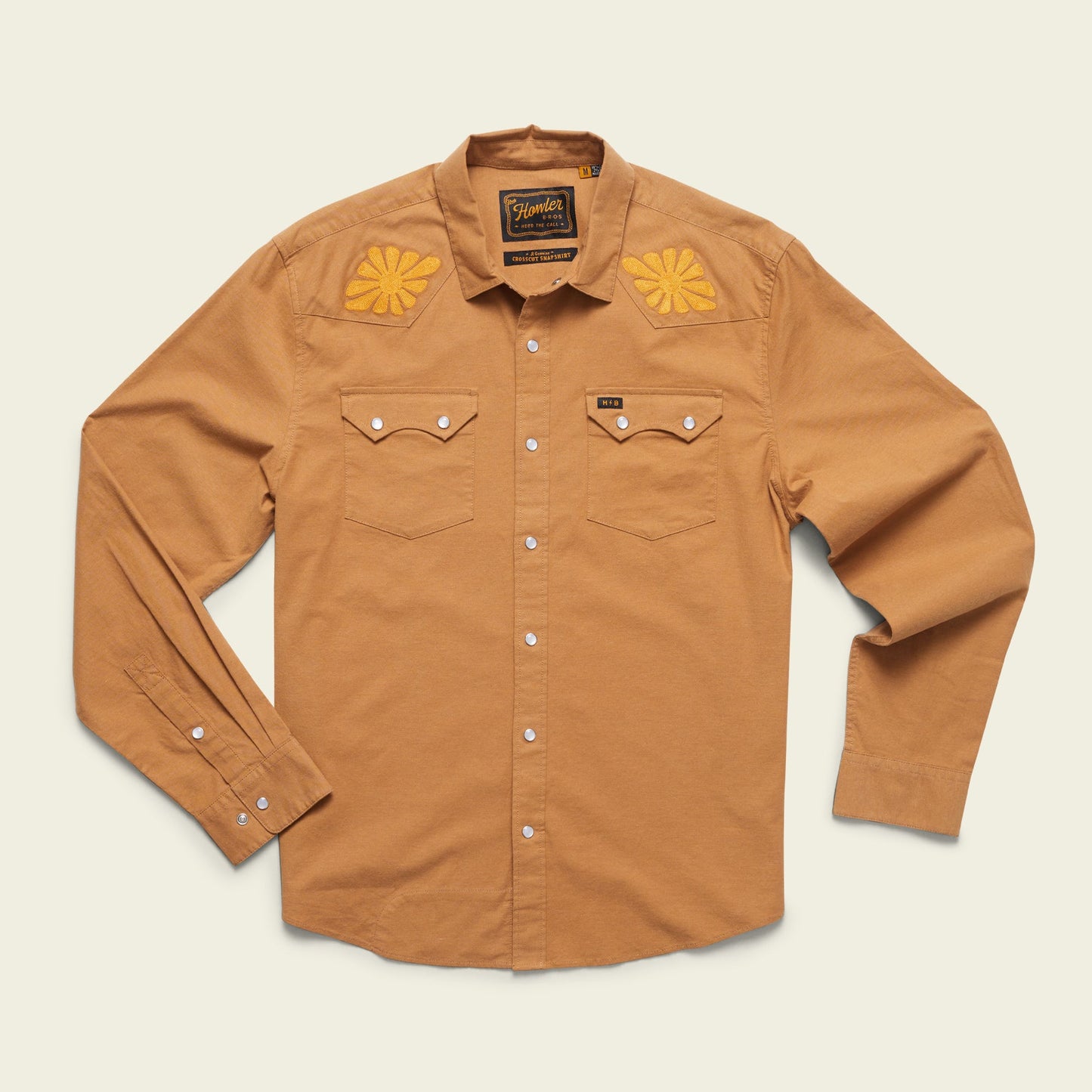 A long-sleeve, button-up tan shirt with pearl snaps, two front chest pockets, and vintage inspired motif embroidery in yellow on the shoulders, displayed on a light background. - View 8