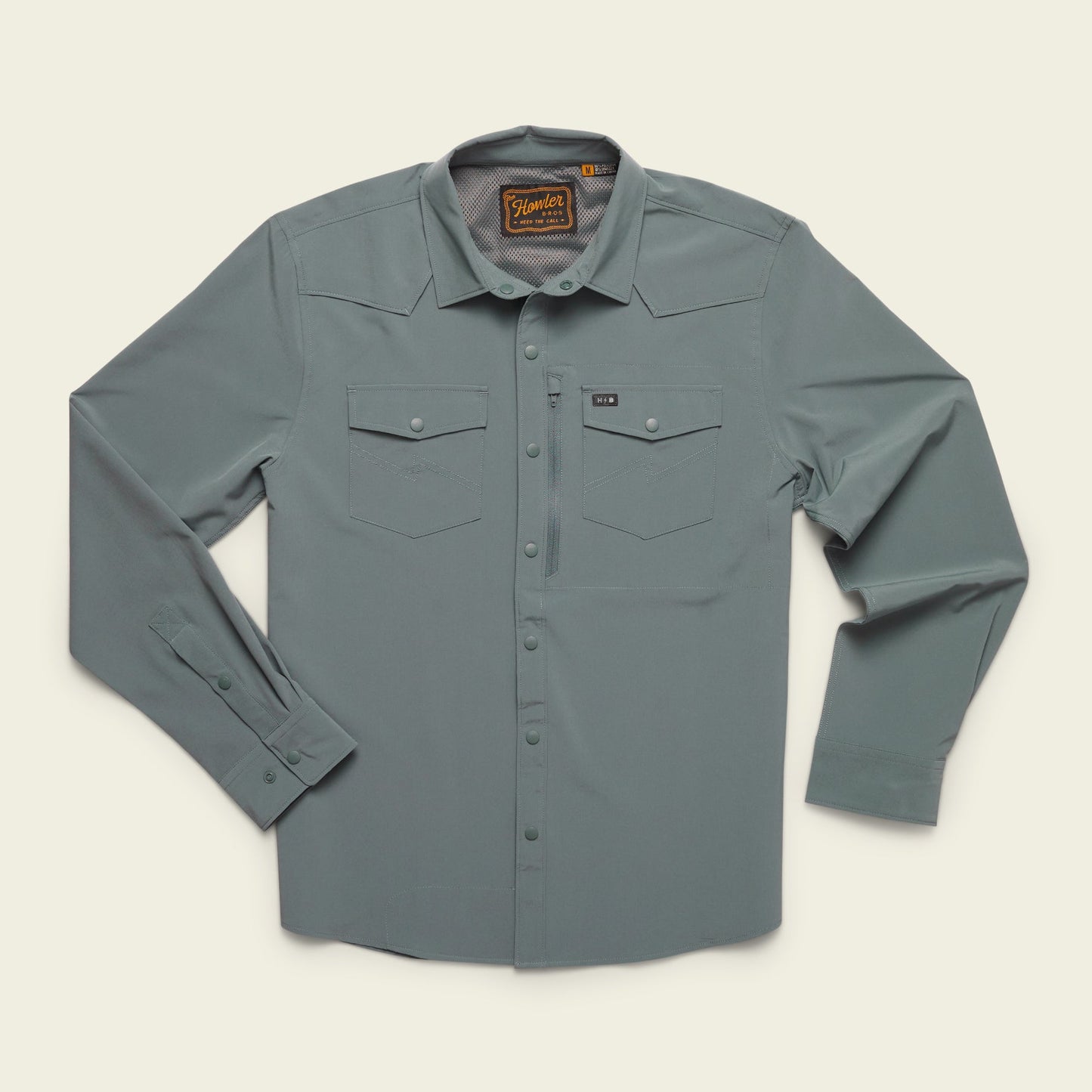 The Emerger Tech Shirt is a lightweight long sleeve, light gray button-up with two chest pockets, buttoned cuffs, and a collar, laid flat on a cream background. Features UPF 35 protection for all-day comfort. - View 2