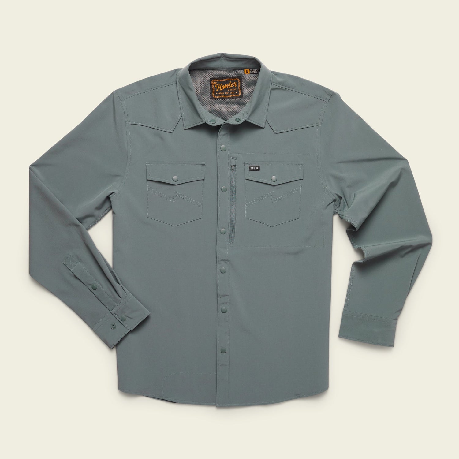The Emerger Tech Shirt is a lightweight long sleeve, light gray button-up with two chest pockets, buttoned cuffs, and a collar, laid flat on a cream background. Features UPF 35 protection for all-day comfort. - View 2