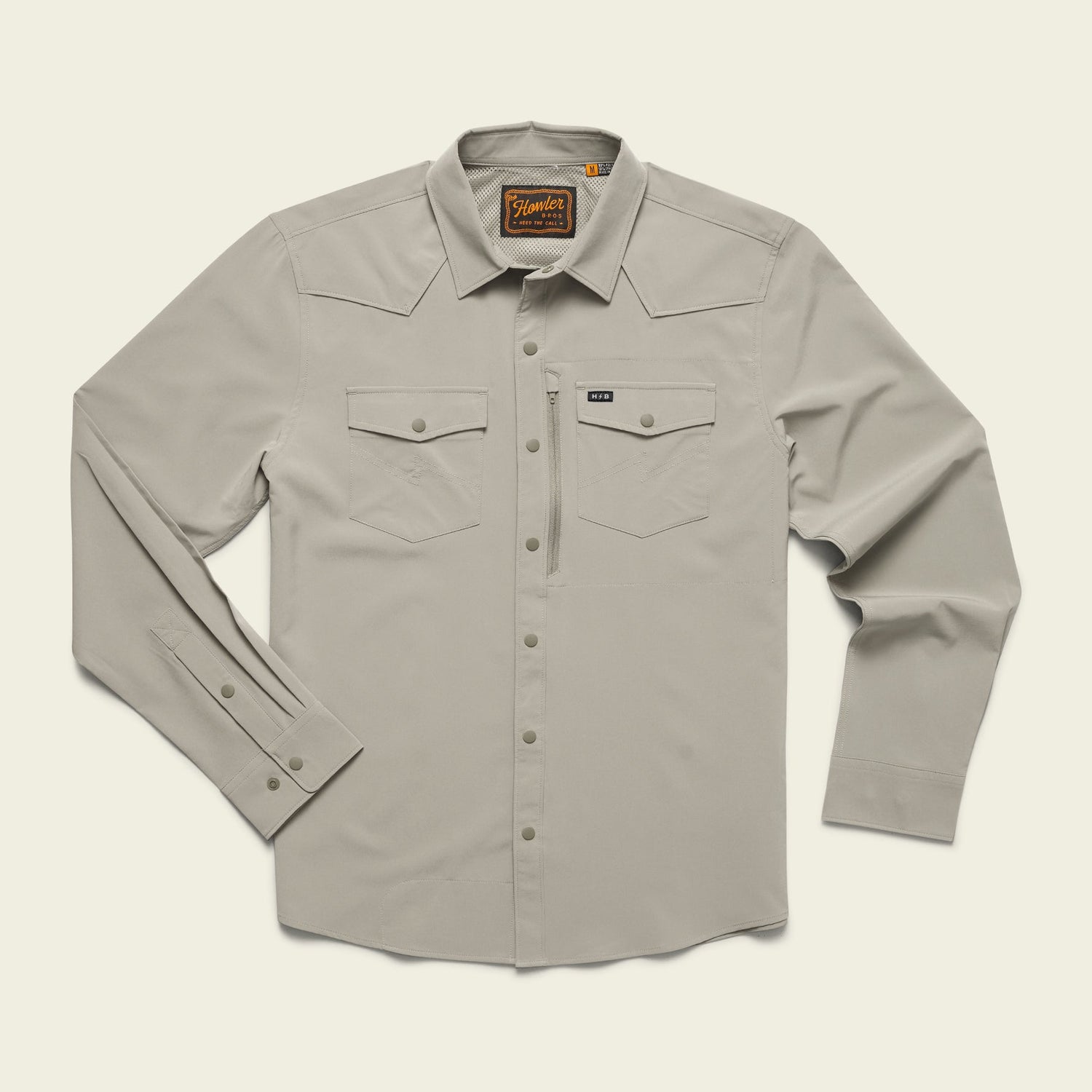 A light beige Emerger Tech Shirt, this longsleeve button-up features a pointed collar, two chest flap pockets, and buttoned cuffs. With UPF 35 protection, it’s laid flat on a cream background with a brown brand label inside the collar. - View 8