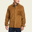 A man wearing a tan wide wale corduroy Iquitos Overshirt with a front chest pocket, layered over a green shirt and dark pants. He stands with his head turned slightly to the side—a perfect travel shirt look.
