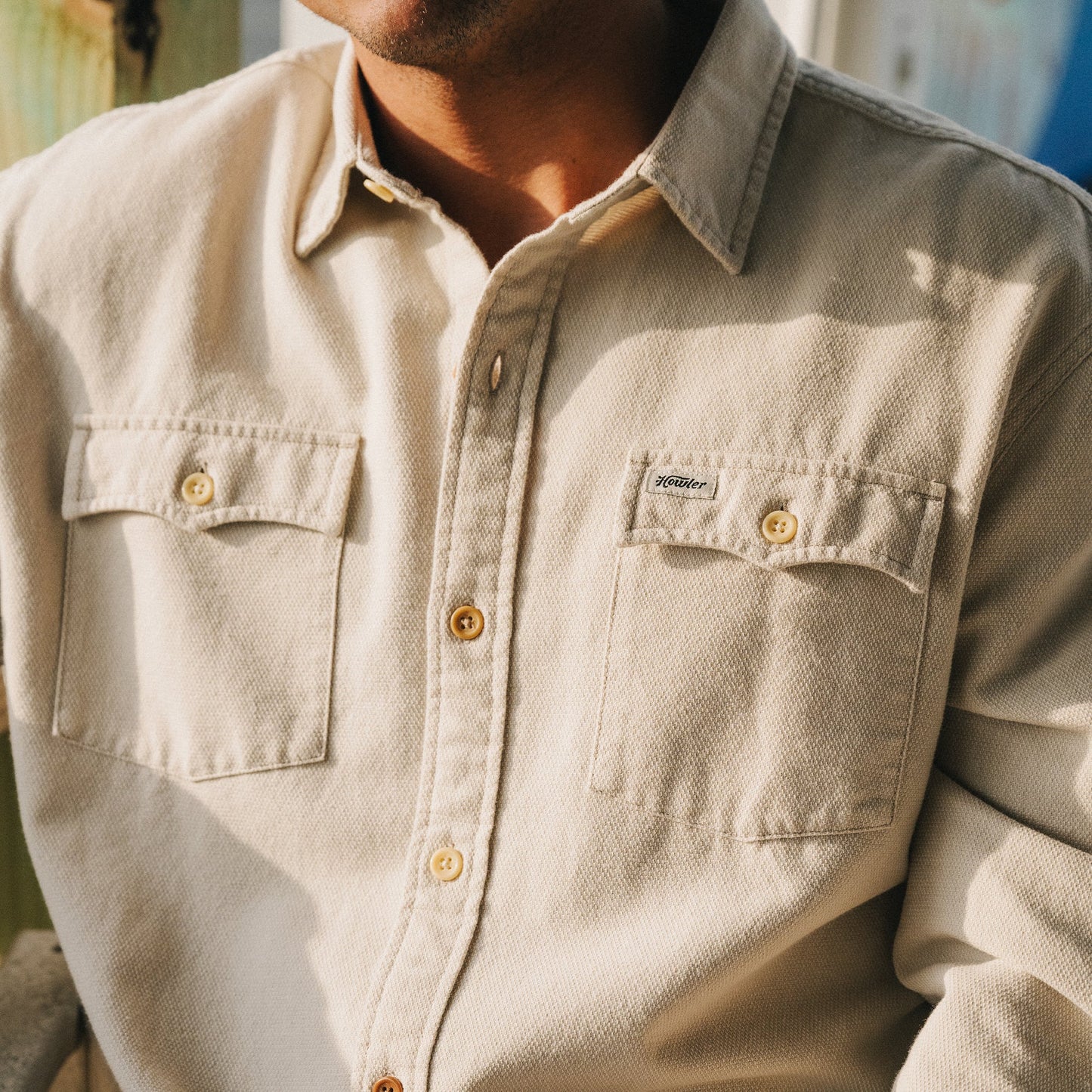 A person wearing the Novato Shirt, a light beige button-up with two chest pockets and a small stitched label on the left pocket, photographed from the shoulders to the waist in natural light. - View 2