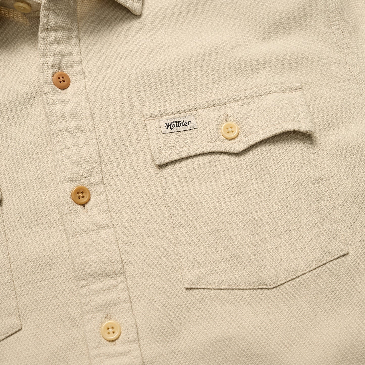 Close-up of a beige Novato Shirt, a classic western shirt with light brown buttons and a chest pocket. The pocket flap features a small Howler label and is secured by a button. - View 3
