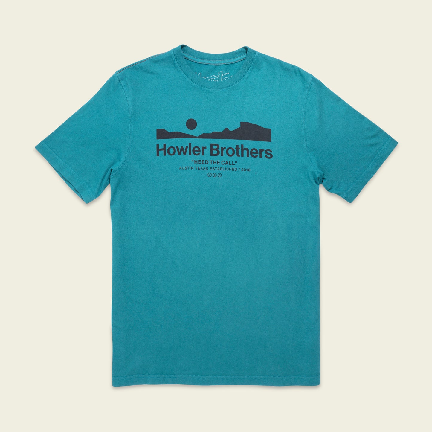 A teal short-sleeve T-shirt featuring experimental artwork: a black graphic of a mountain landscape and sun. The text reads Howler Brothers and Heed The Call, Austin, Texas, Established 2010 beneath the graphic. - View 1