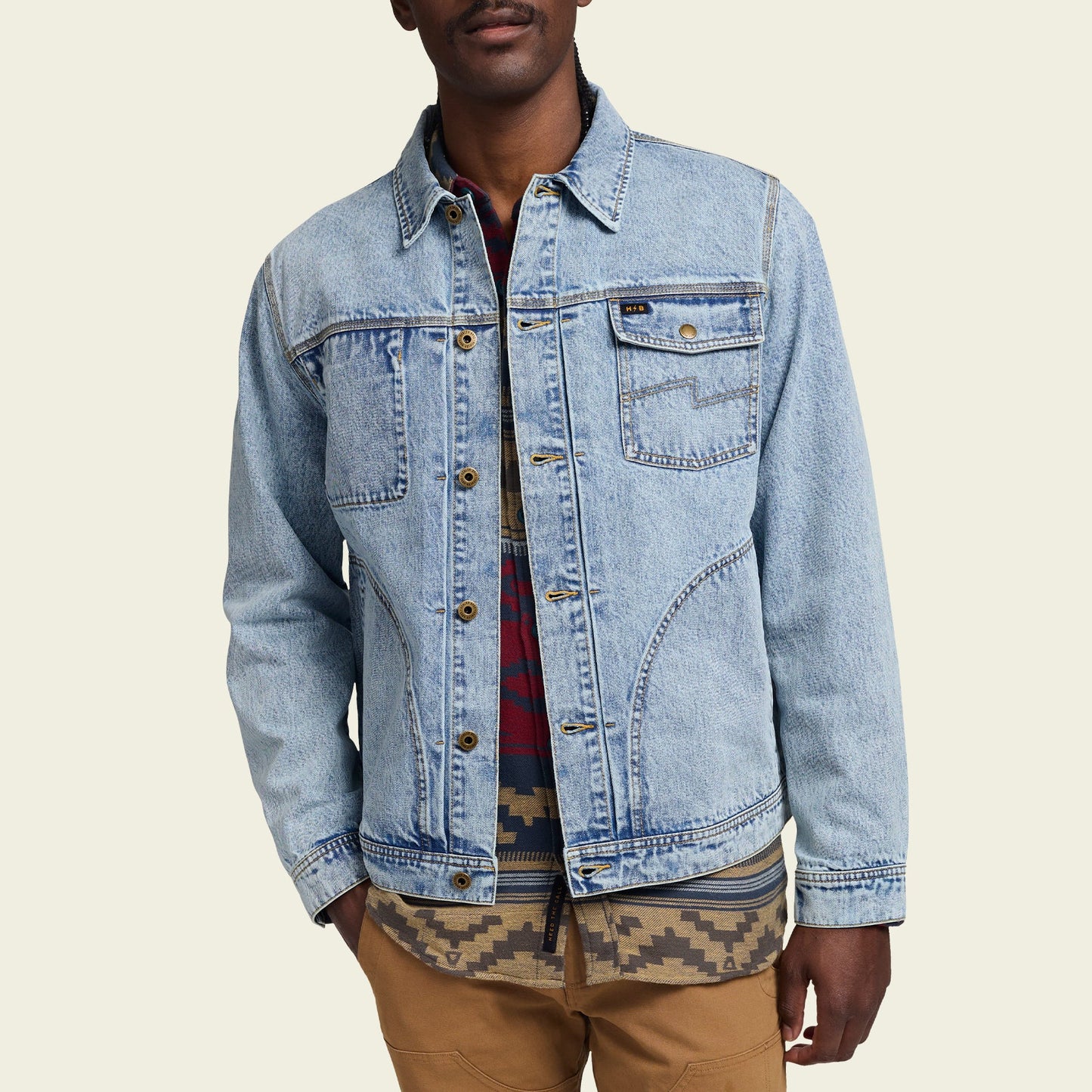 A person wearing a light blue Depot Jacket with lightning bolt stitch over a red and blue plaid shirt and a patterned shirt, paired with tan pants, stands against a plain light background. - View 5