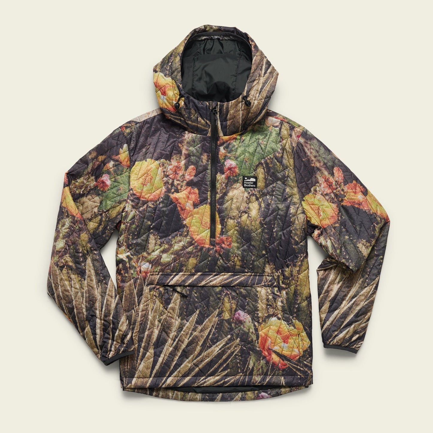 A quilted hooded pullover with PrimaLoft insulation, featuring a vibrant cactus and flower print in green, yellow, and orange. This lightweight travel jacket has a front zip, a large front pocket, and a black rectangular logo patch on the chest. - View 2