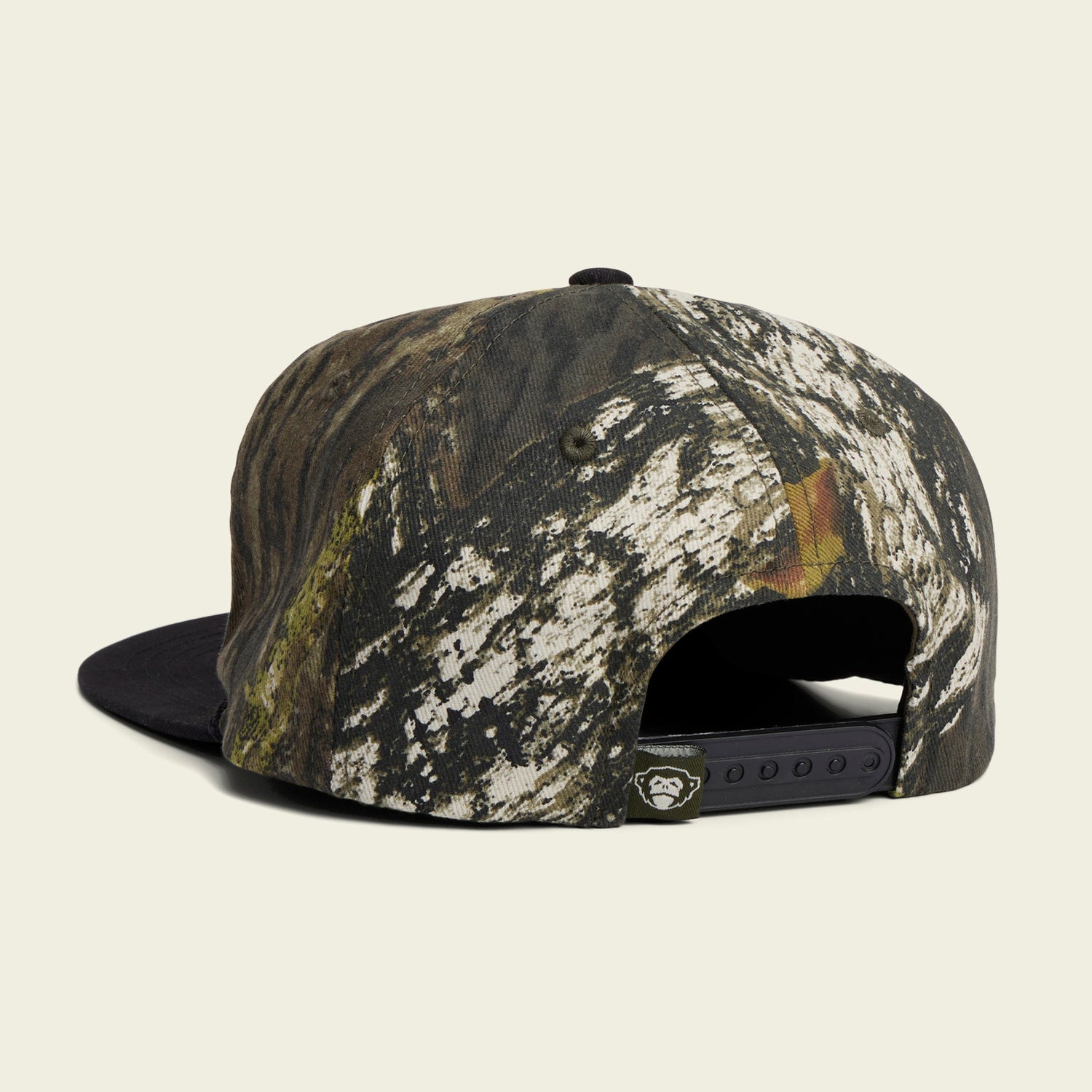 A snapback cap with a camouflage pattern is shown from the back, featuring an adjustable snapback closure, a small black tag near the opening, and a soft crown for added comfort. - View 3