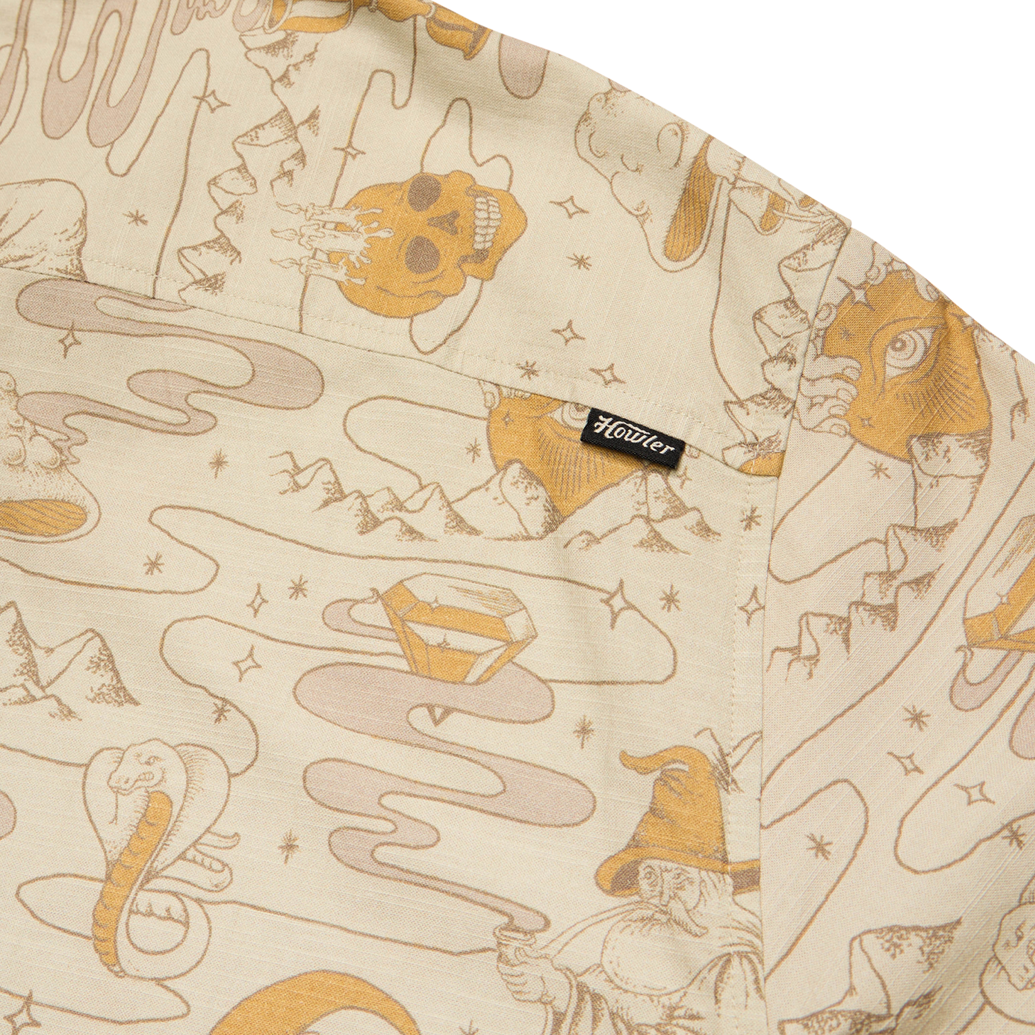 Beige slub fabric with whimsical, line-drawn illustrations including a skull, diamond, wizard, snake, all-seeing eye, and mountains—reminiscent of vintage Hawaiian shirts. A small black tag with “Houdini” is sewn onto a pocket. - View 6