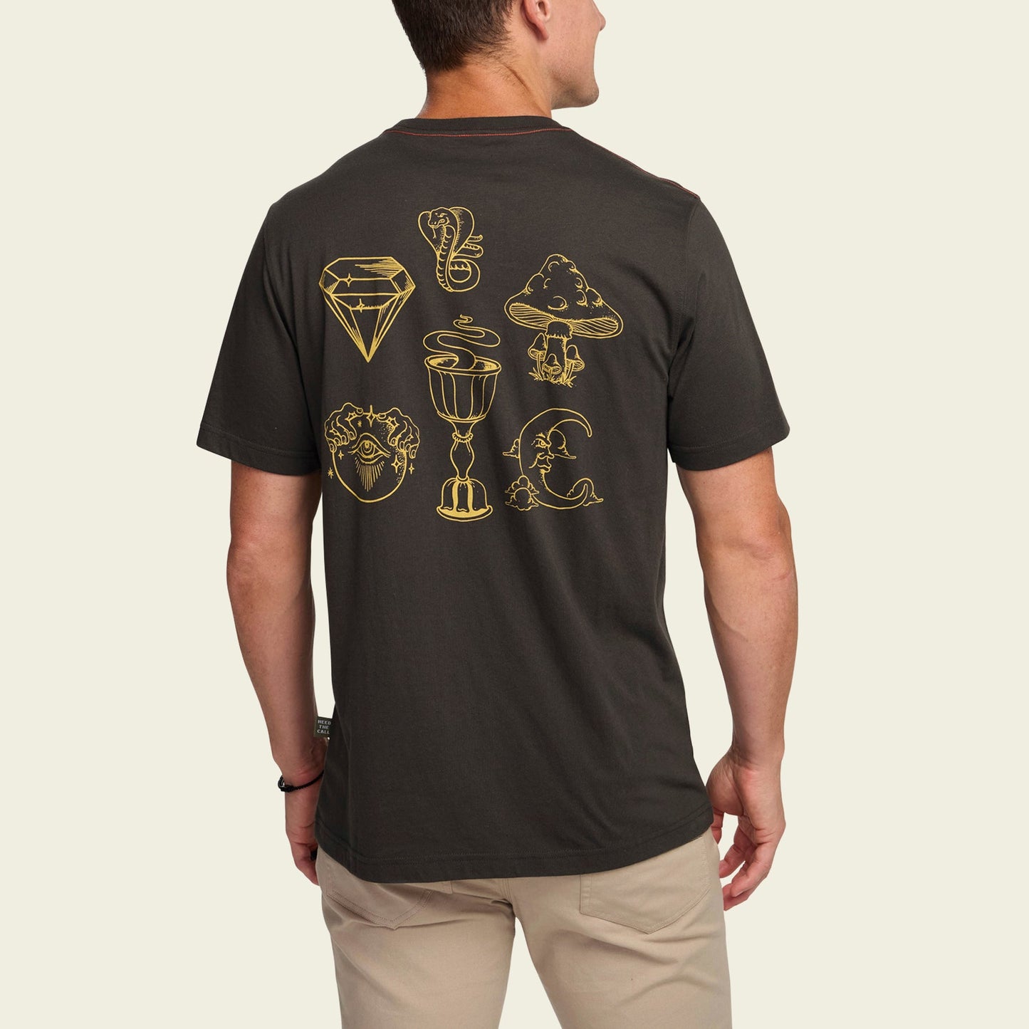A man wears a black Howler t-shirt with gold line art—diamond, serpent, mountain, heart, chalice, crescent moon, and a hand with an eye. The cotton-poly blend ensures comfortable t-shirts while showcasing bold back artwork. - View 5