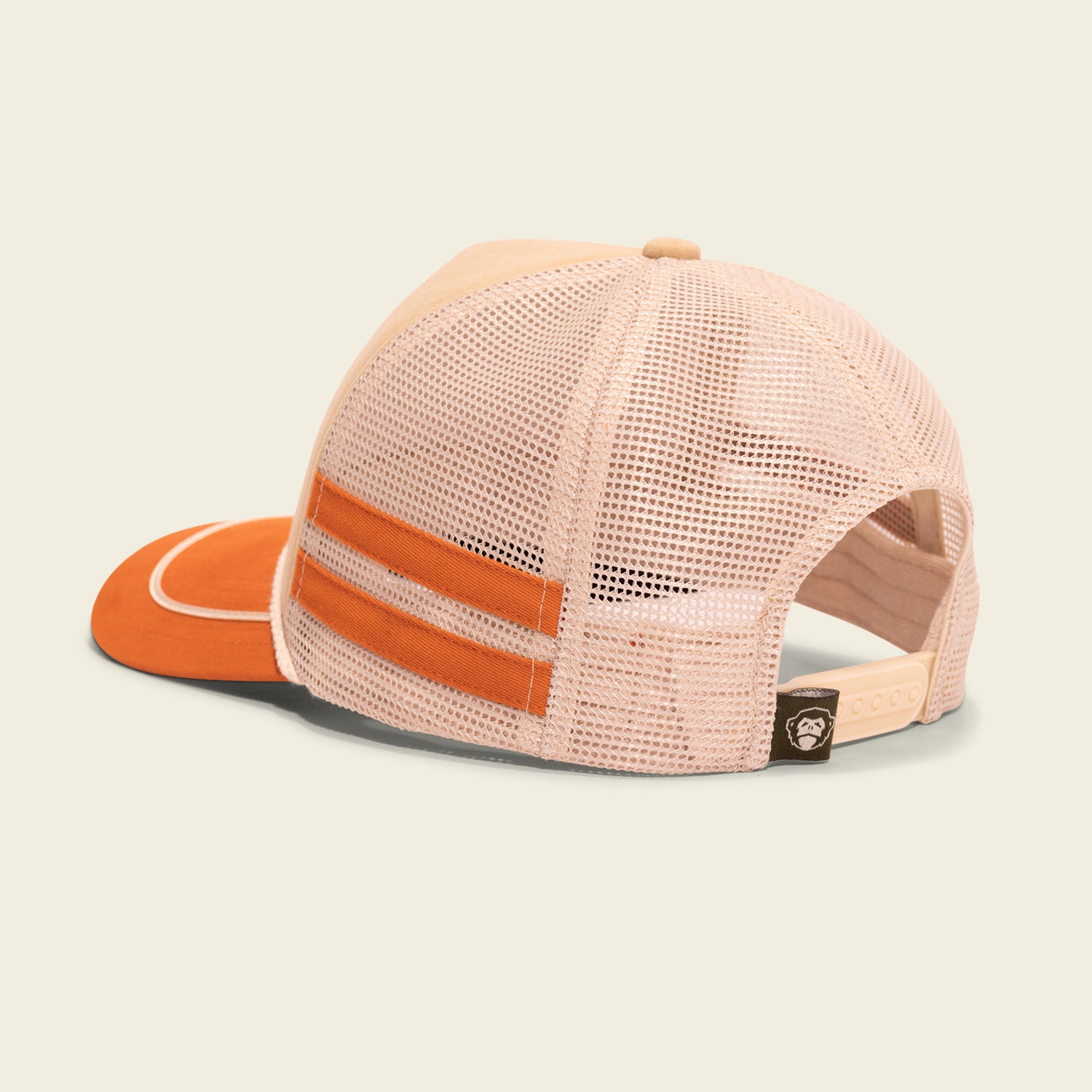 A beige and orange vintage-inspired trucker hat with a mesh back, two orange horizontal stripes, and an adjustable strap with a small black tag featuring a logo. The Foam Dome hat is positioned with the back facing the viewer. - View 4