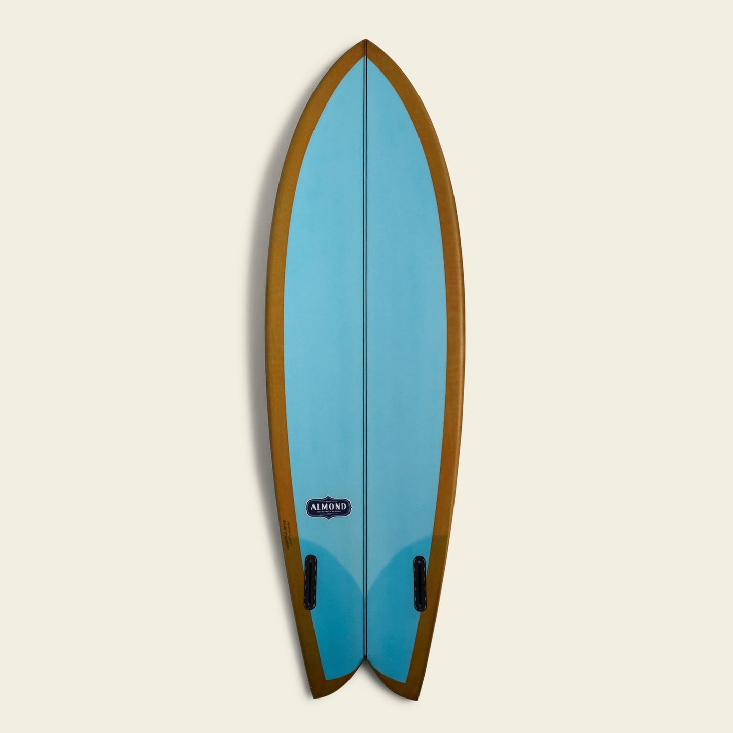 A blue Almond Surfboards surfboard with a brown border and a swallowtail design, displayed vertically against a plain, light background. The board features two black fins and an Almond brand logo near the bottom. - View 6