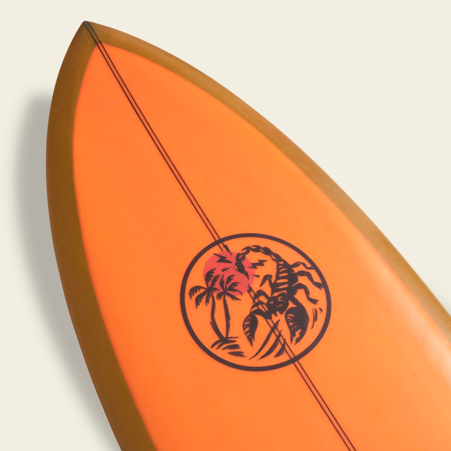 Close-up of the tip of an orange Almond Surfboards surfboard with a circular black graphic featuring palm trees and a setting sun, on a plain light background. - View 8