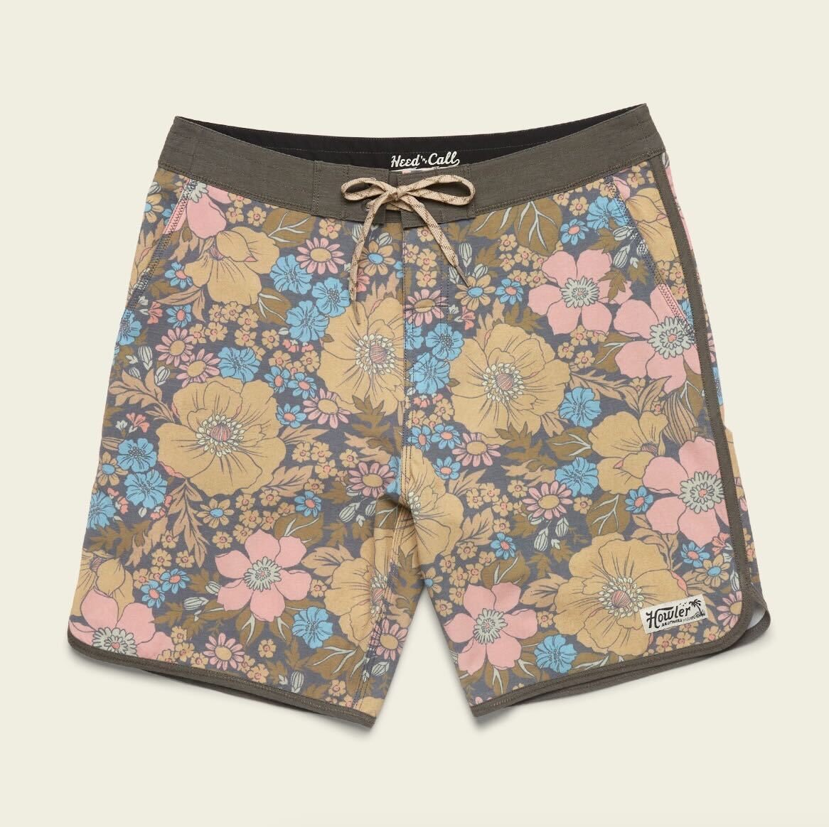 A pair of Bruja Boardshorts with a drawstring waist, made from stretchy fabric and featuring a colorful floral pattern in yellow, blue, and pink on brown, plus Howler branding on the left leg. - View 15