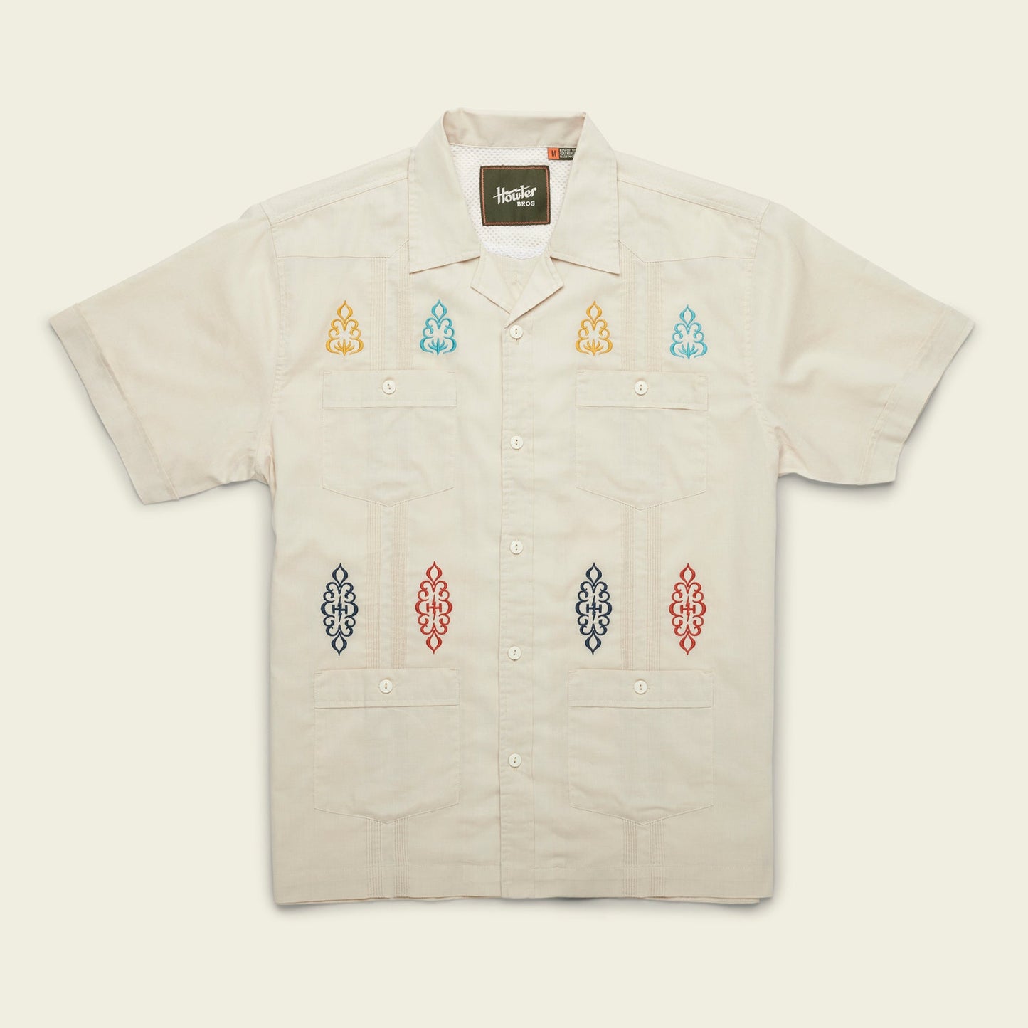 A modern fit, short-sleeve Guayabera shirt in light beige, featuring four front pockets and colorful embroidered patterns on the chest and lower front, crafted from technical cotton-poly stretch fabric for added comfort. - View 6