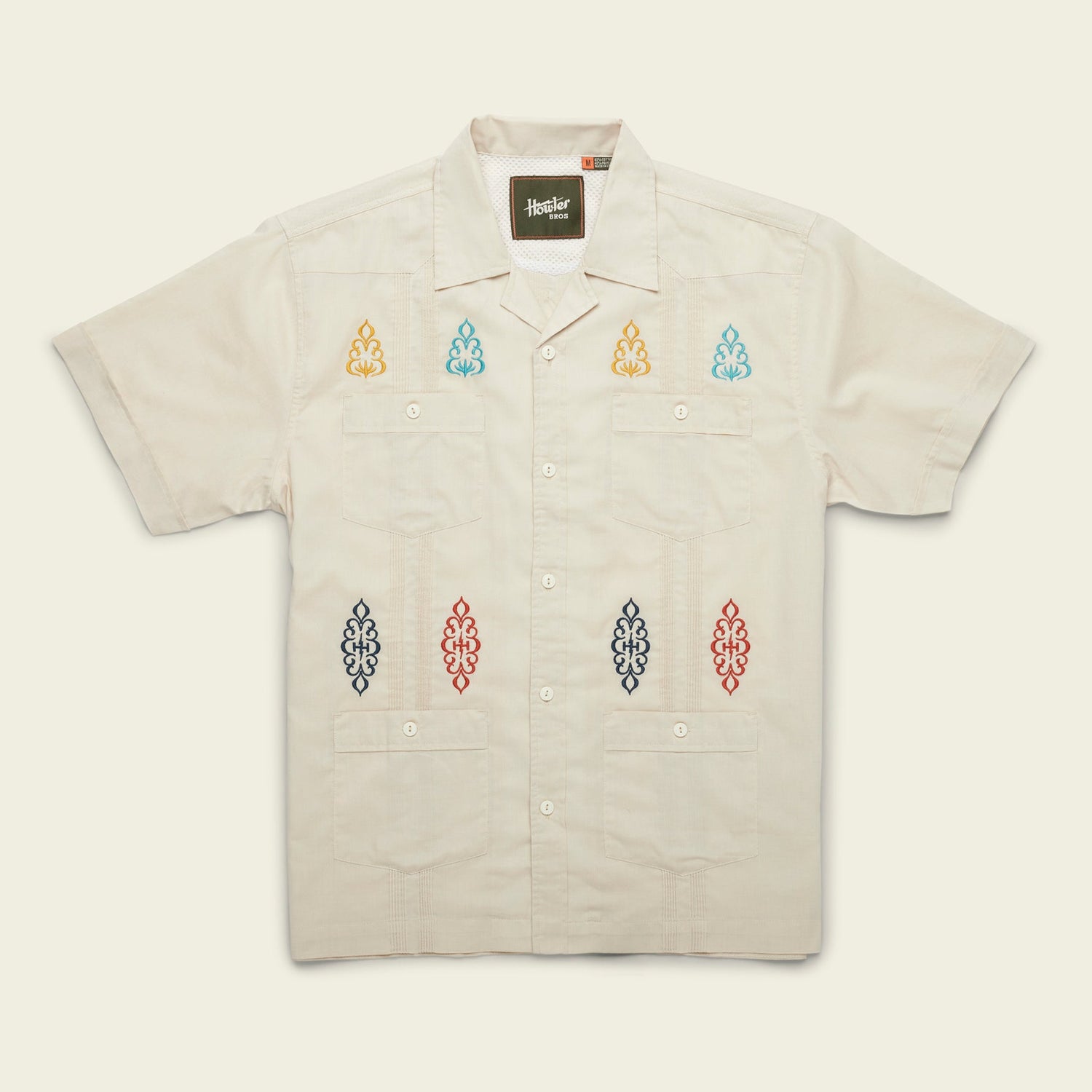 A modern fit, short-sleeve Guayabera shirt in light beige, featuring four front pockets and colorful embroidered patterns on the chest and lower front, crafted from technical cotton-poly stretch fabric for added comfort. - View 6