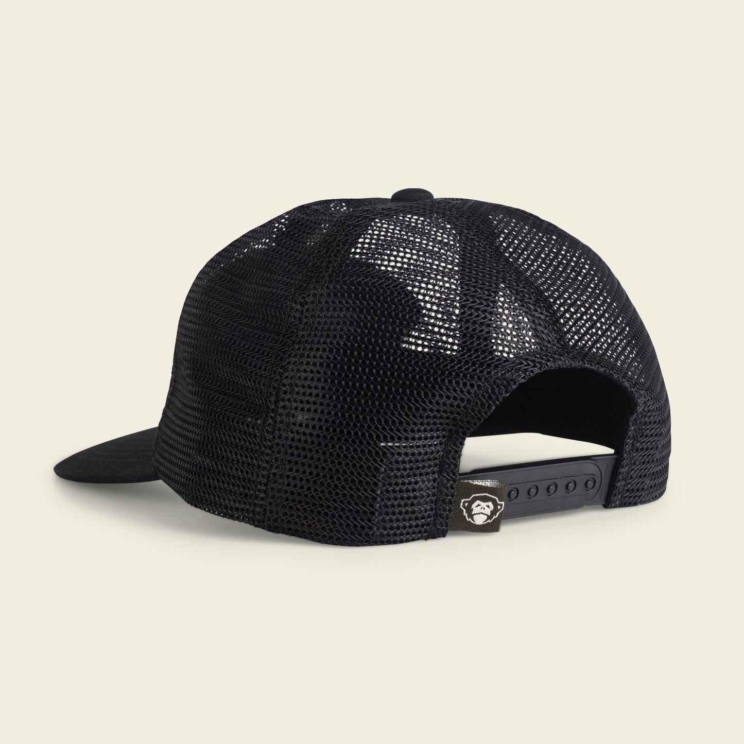 A black mesh trucker cap viewed from the back, featuring an adjustable snapback closure, unstructured snapbacks design, and a small tag with a white monkey face logo above the closure. - View 3
