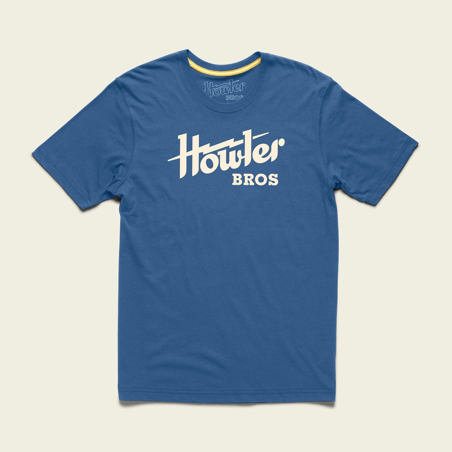 A blue short-sleeve t-shirt made from a soft cotton-poly blend, featuring the bold white Howler Bros logo across the chest. The shirt is laid flat on a light background, showcasing one of the classic Howler designs. - View 4