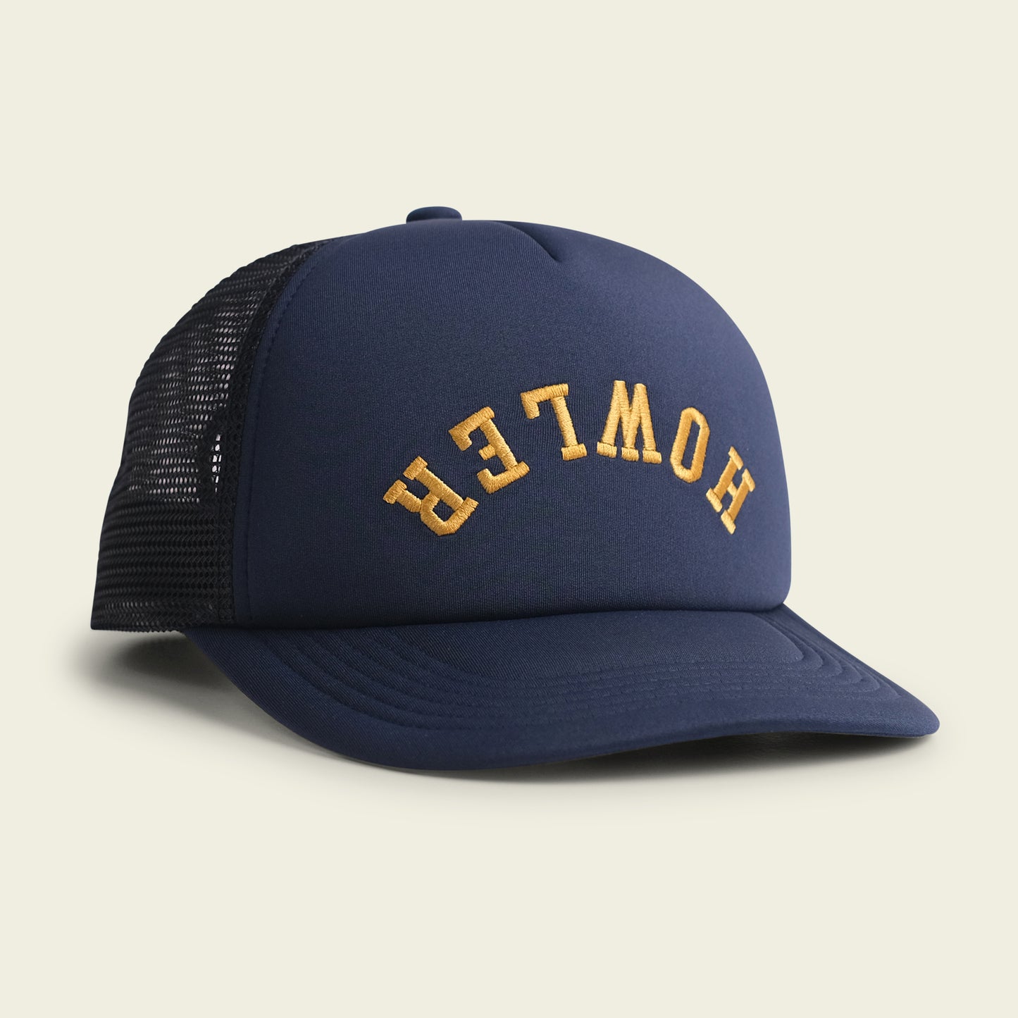 A navy blue, vintage-inspired hat with a foam front and black mesh back features the word HOWLER in curved yellow letters on the front panel. The high crown hat is displayed on a light background. - View 1