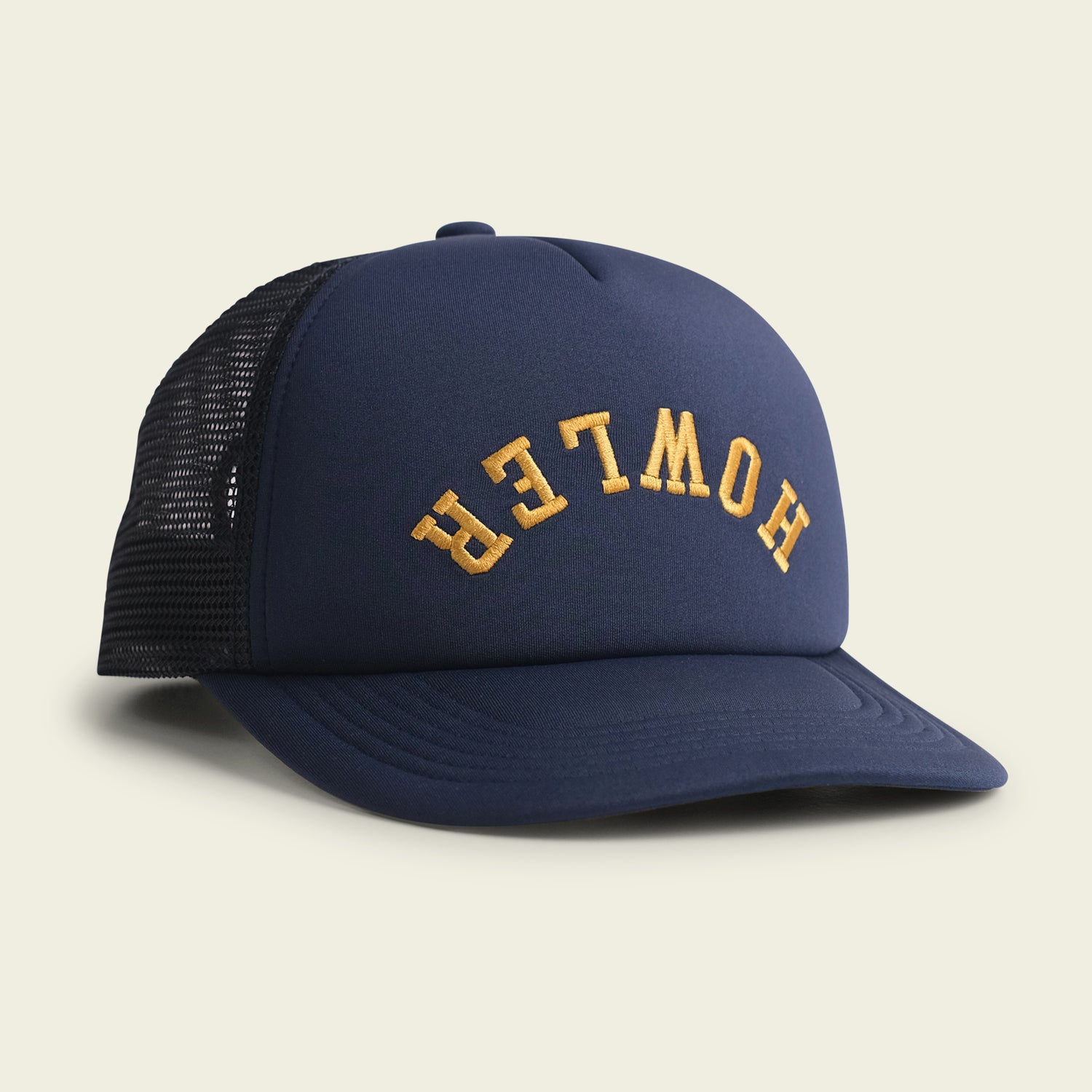 A navy blue, vintage-inspired hat with a foam front and black mesh back features the word HOWLER in curved yellow letters on the front panel. The high crown hat is displayed on a light background.