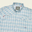 A light blue and white plaid Matagorda Shirt with a collar, front chest pocket with flap, quick drying fabric, and a Howler Bros label on the inside neck and above the pocket—perfect as your travel shirt.