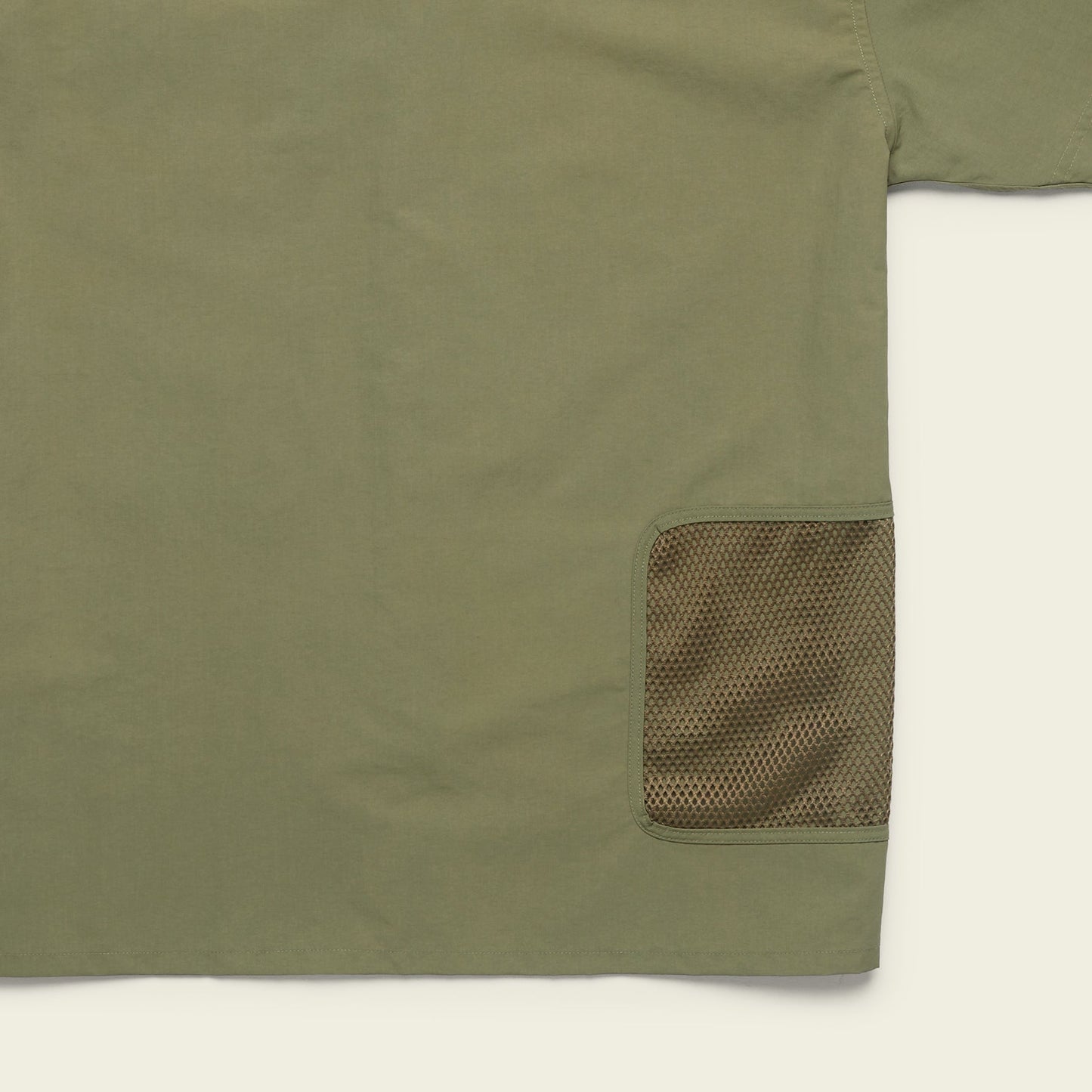 Olive green Forager Utility Shirt with a mesh brown pocket on the lower right side. Only part of this tech shirt is visible, focusing on pocket detail and fabric texture, perfect for hiking trails against a light background. - View 8