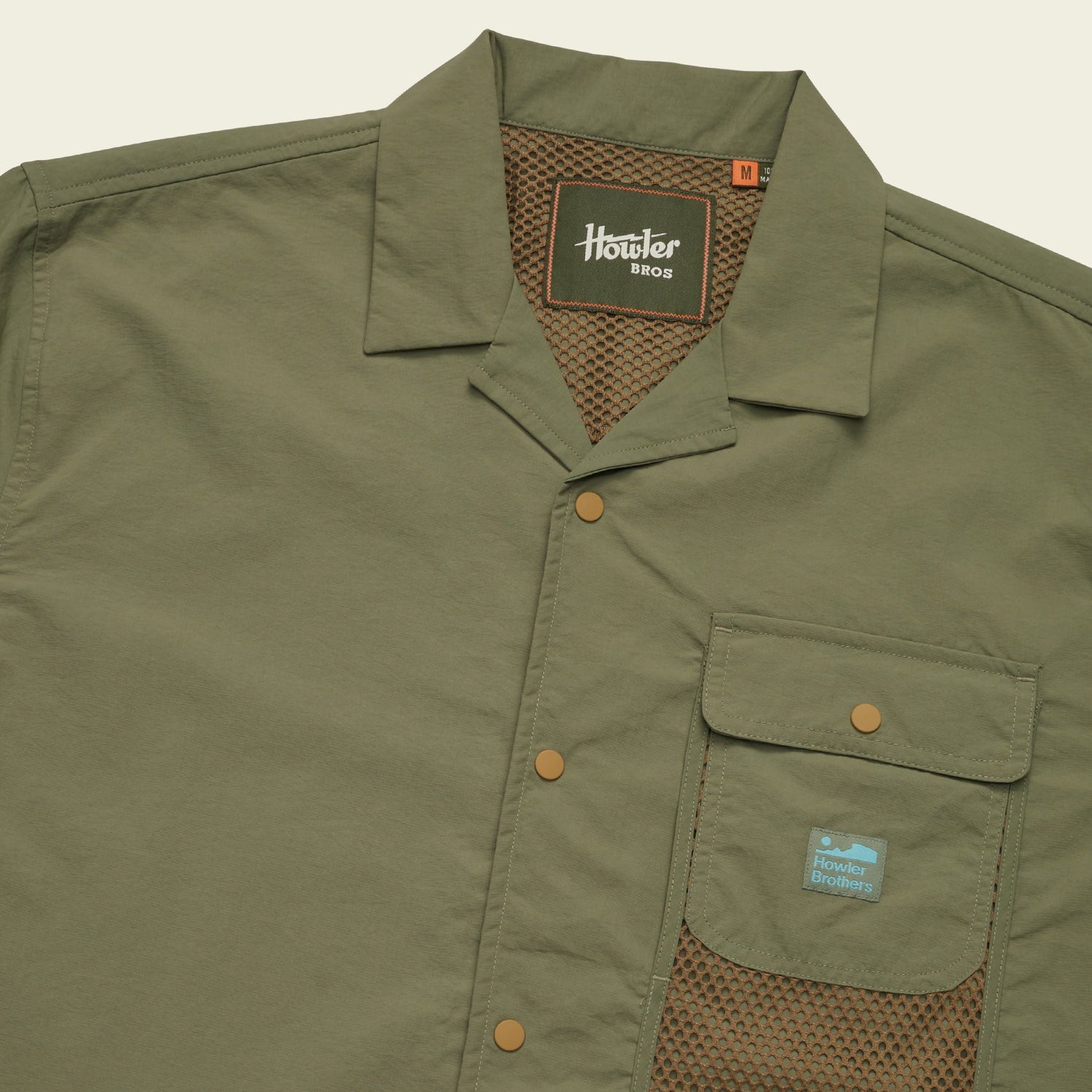 Olive green Forager Utility Shirt with short sleeves, collar, snap buttons, mesh lining, and a Howler Brothers logo patch. This tech shirt offers casual, utilitarian style—perfect for hiking trails or laid-back days out. - View 6