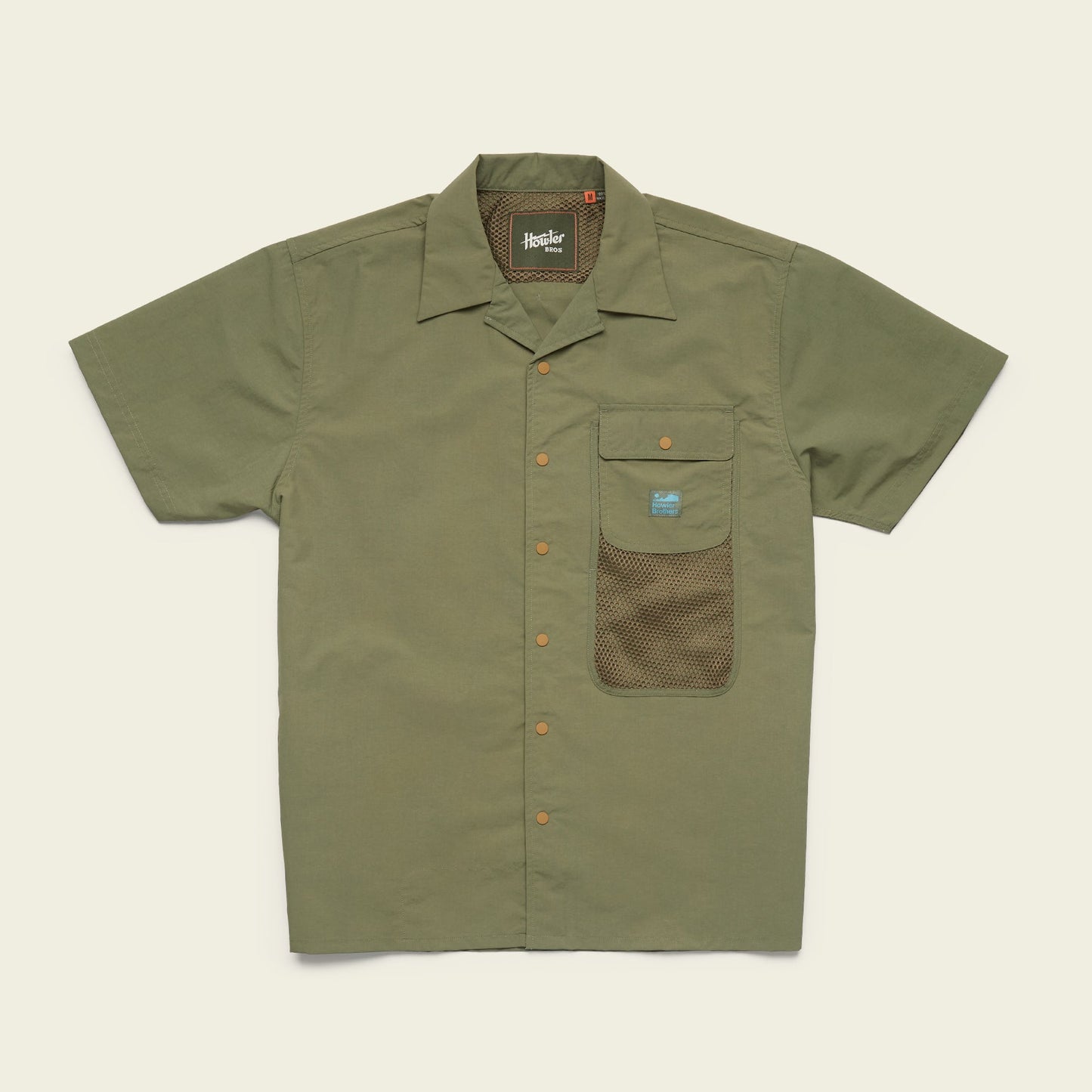 Short-sleeve olive green Forager Utility Shirt with a collar, orange buttons, and a front pocket featuring a mesh lower section and a small blue label. Perfect as a tech shirt for hiking trails. Laid flat on a light beige background. - View 1