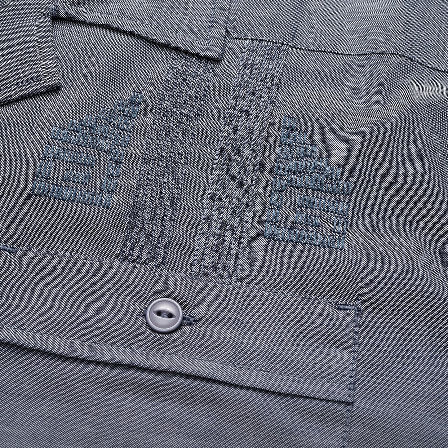 Close-up of a gray technical cotton-poly stretch fabric, showing two embroidered chevron insignias above a pocket with a button. The stitching, texture, and unique embroidery details are clearly visible. - View 3