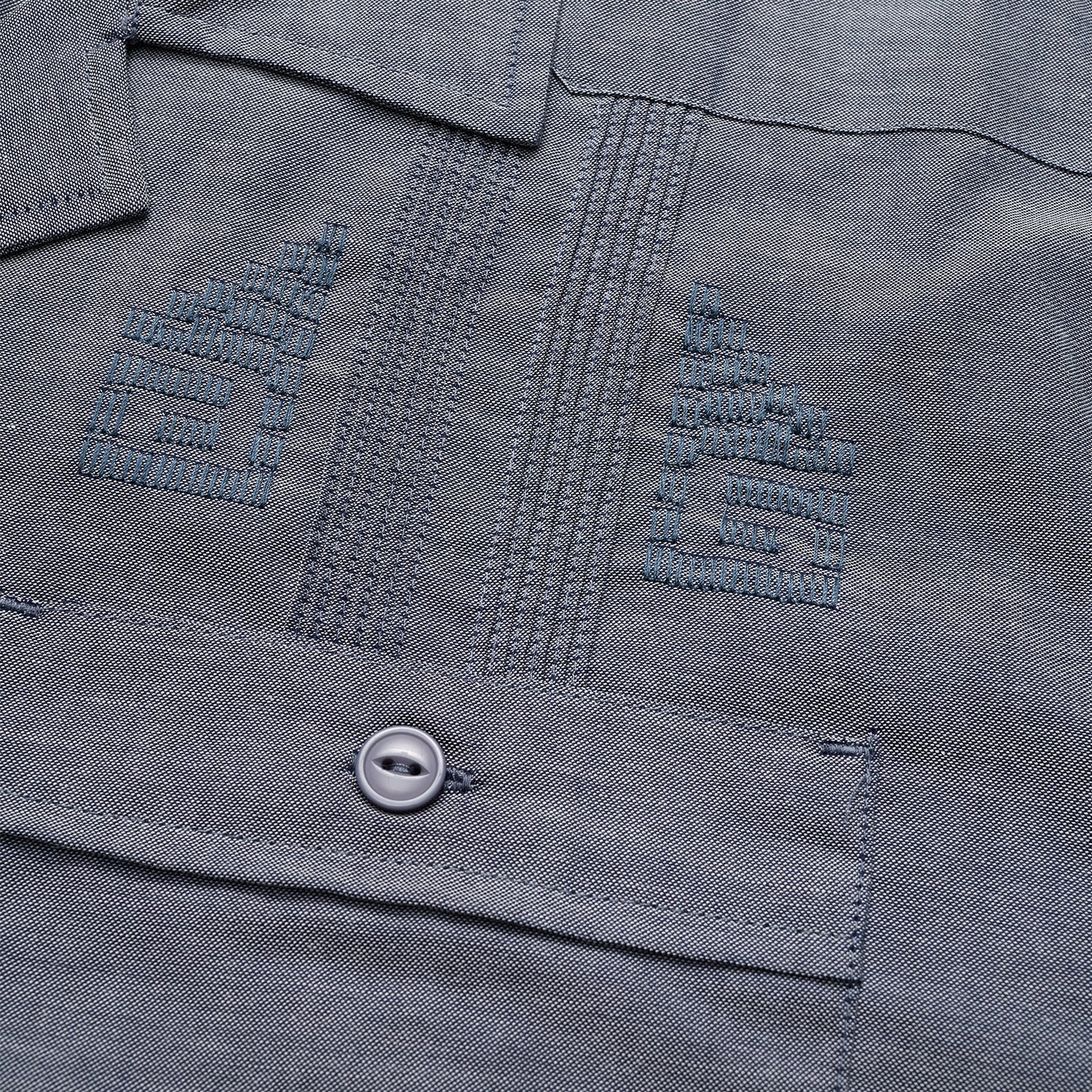 Close-up of a gray technical cotton-poly stretch fabric, showing two embroidered chevron insignias above a pocket with a button. The stitching, texture, and unique embroidery details are clearly visible. - View 3