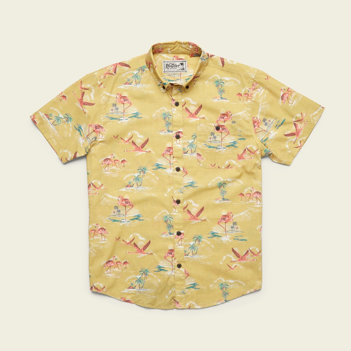 A lightweight cotton-poly Mansfield Shirt, this short-sleeve button-up features unique seasonal patterns with pink flamingos, palm trees, and blue water accents, laid flat on a cream background. - View 5