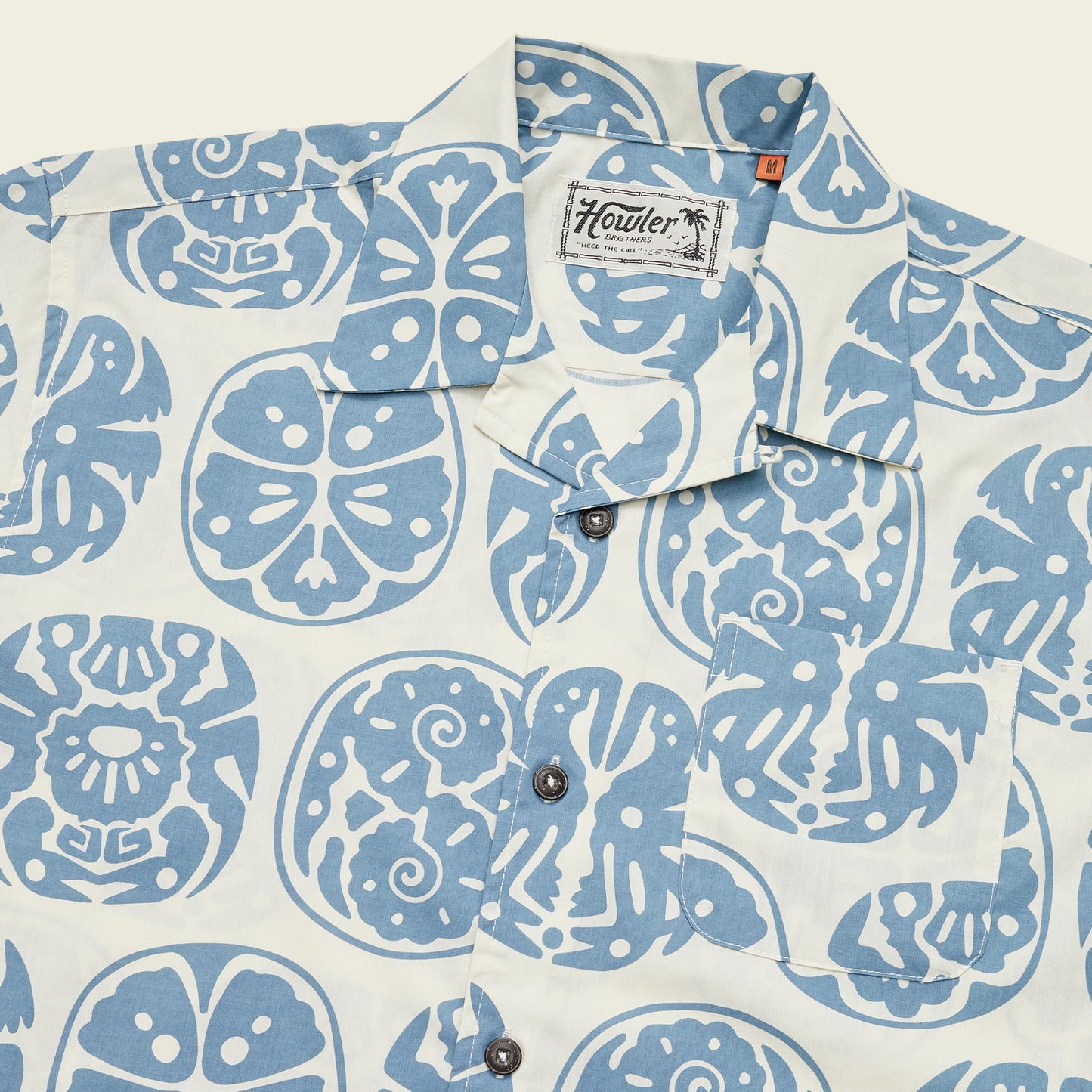 A white camp collar shirt with a blue abstract Sea Idols print featuring faces, birds, and geometric shapes. This style nods to vintage Hawaiian shirts and includes a chest pocket plus a Howler Bros label on the inside collar. - View 6
