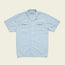 Light blue Shores Club Shirt with short sleeves and two chest pockets featuring geometric embroidery and small brown buttons. This camp collar shirt also has white front buttons, a classic collar, and decorative stitching on the pockets.
