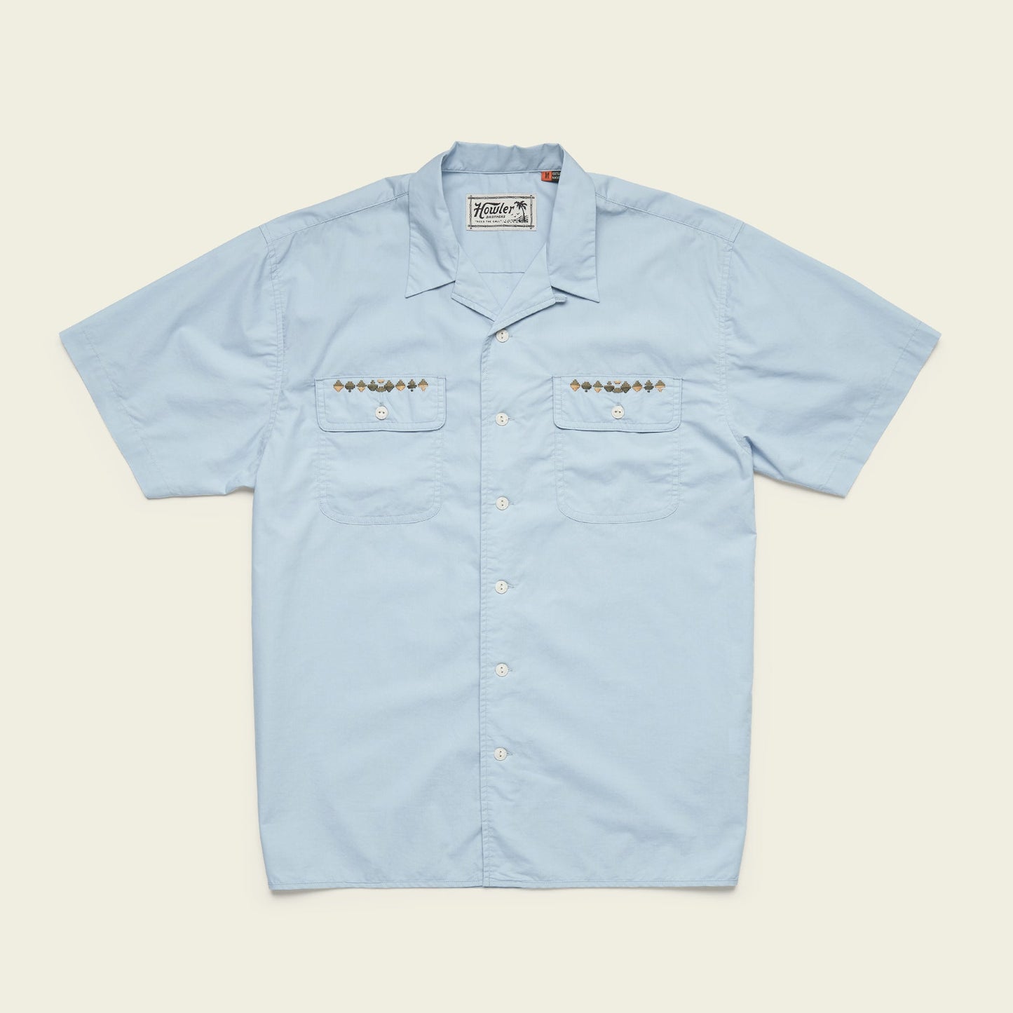 Light blue Shores Club Shirt with short sleeves and two chest pockets featuring geometric embroidery and small brown buttons. This camp collar shirt also has white front buttons, a classic collar, and decorative stitching on the pockets. - View 4